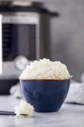 A bowl of Jasmine rice with chopsticks on a countertop