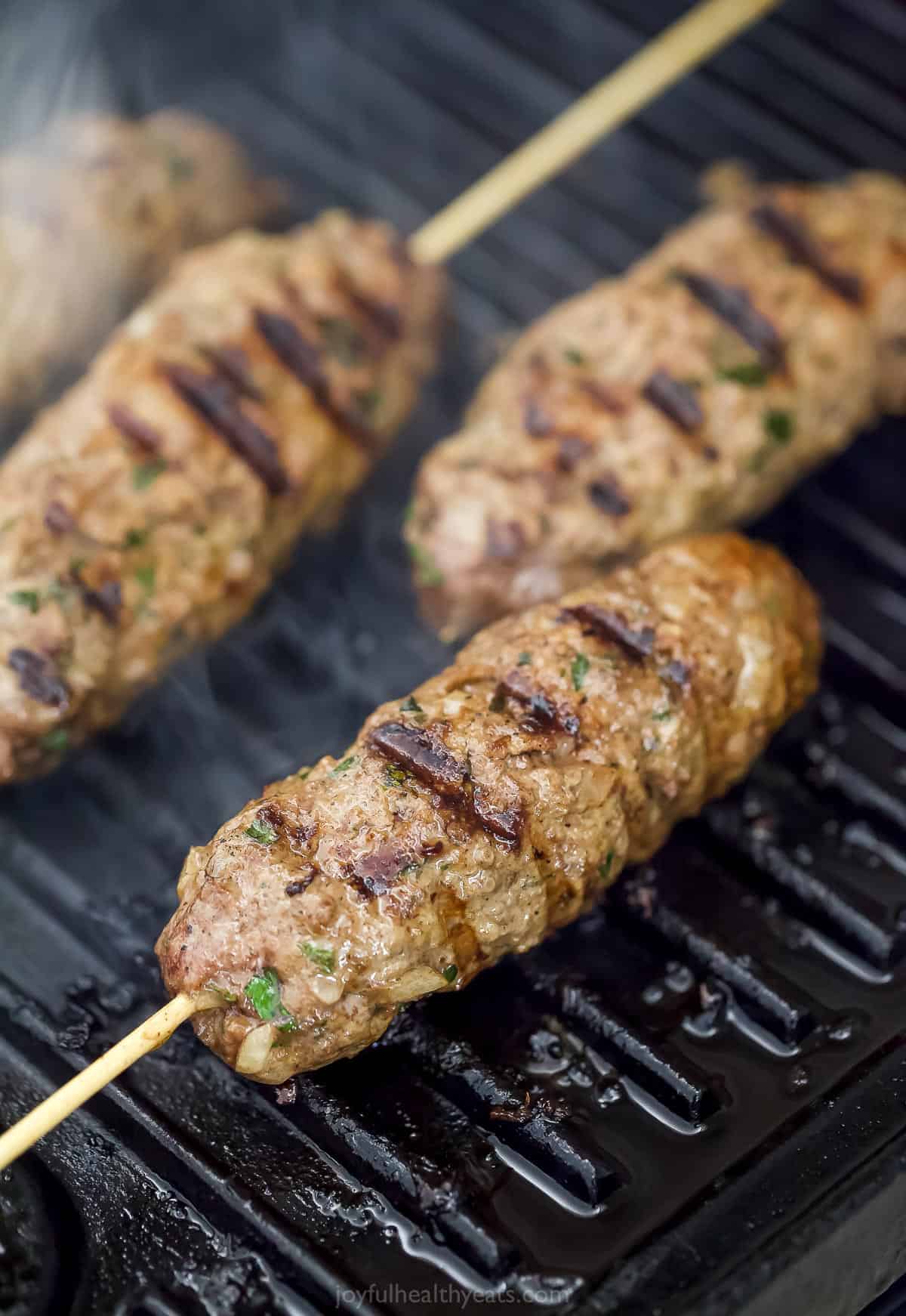 Four ground beef keftas cooking on a stovetop grill pan