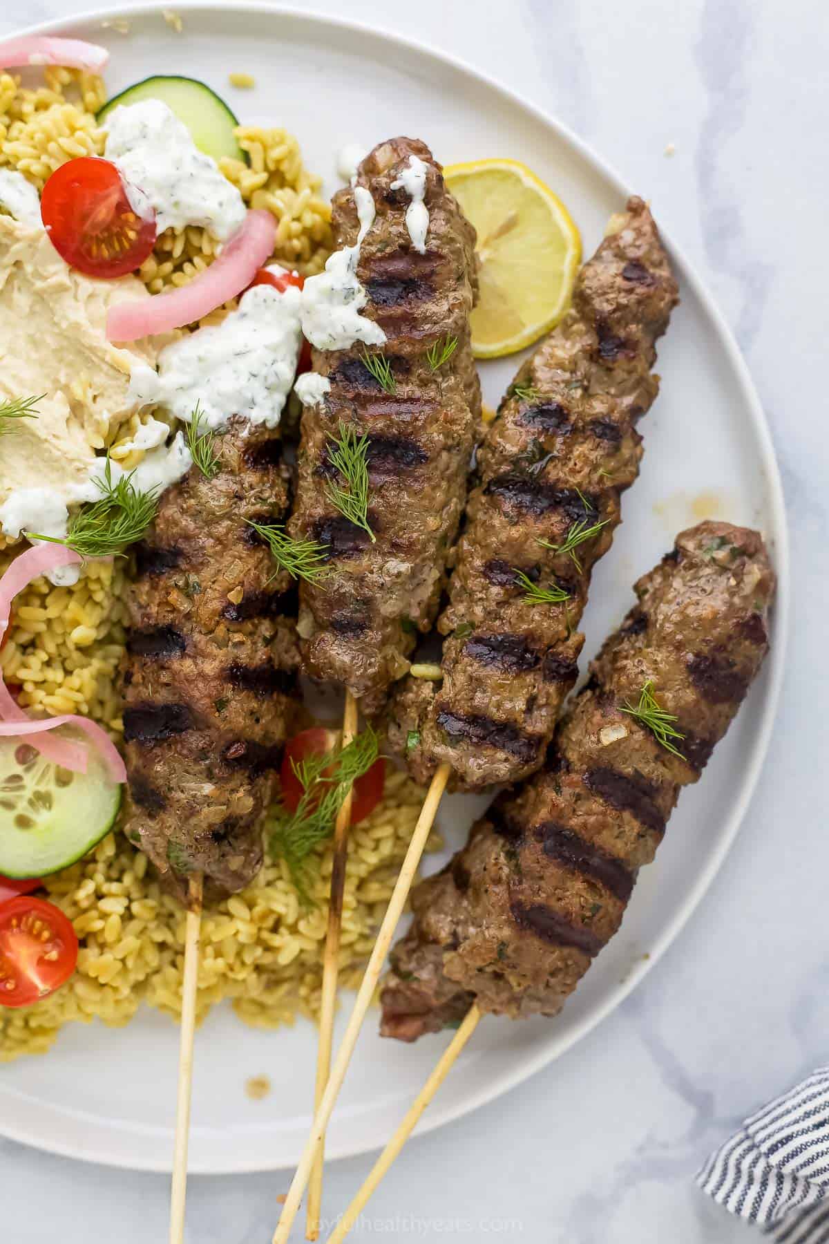 A close-up shot of Moroccan kabobs on a plate on top of a marble surface