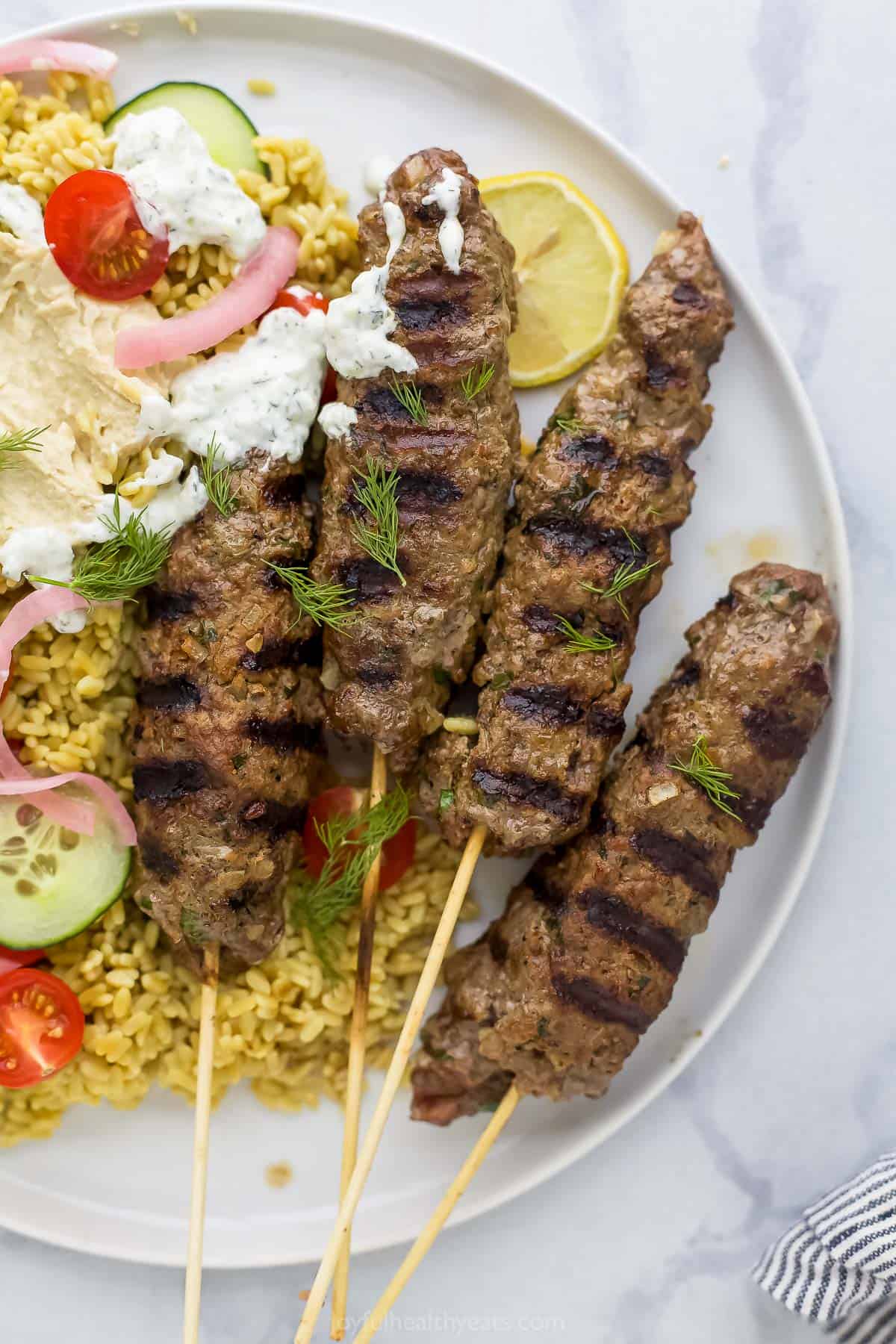 A close-up shot of Moroccan kabobs on a plate on top of a marble surface