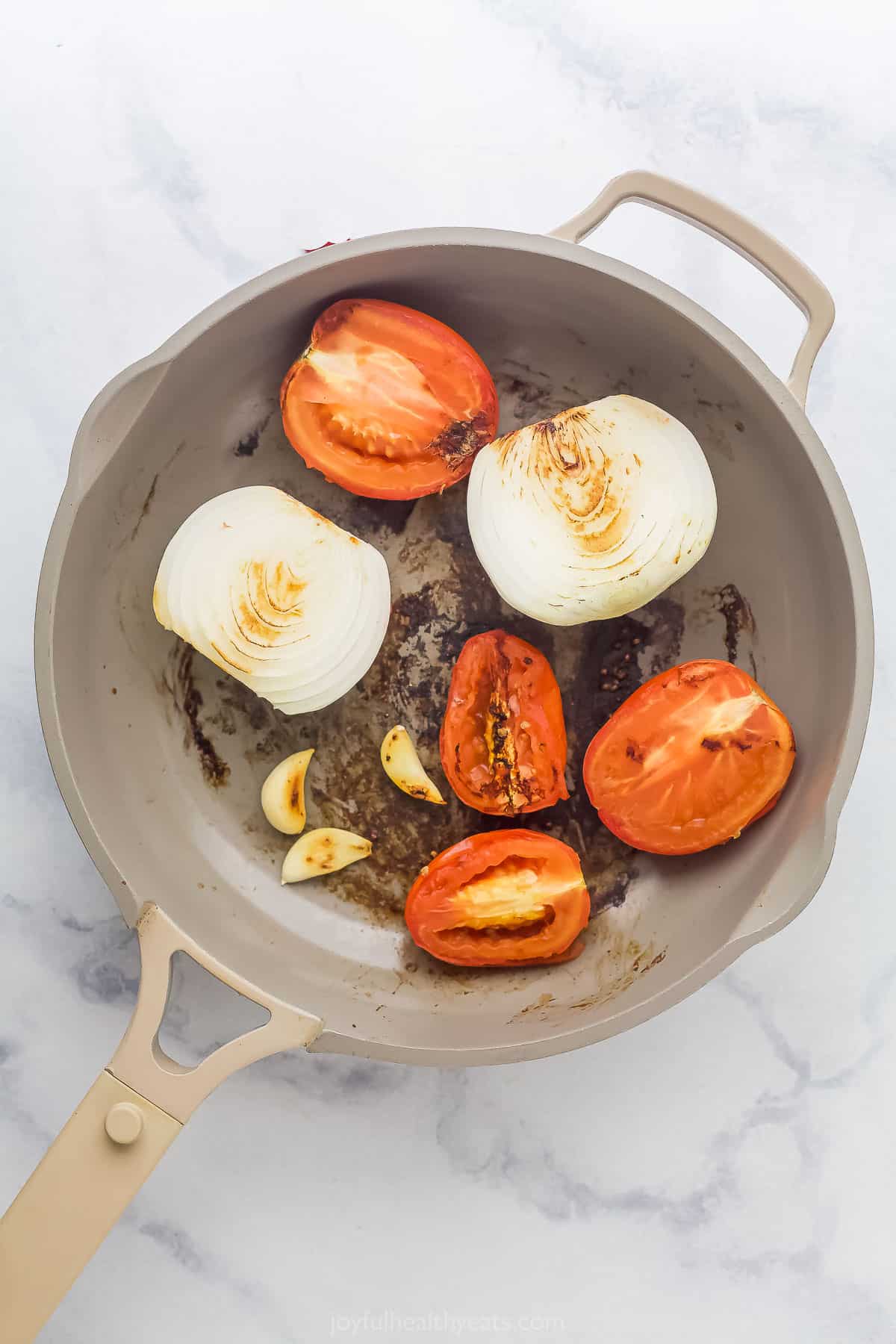 charred tomatoes, garlic, and onion in a saute pan