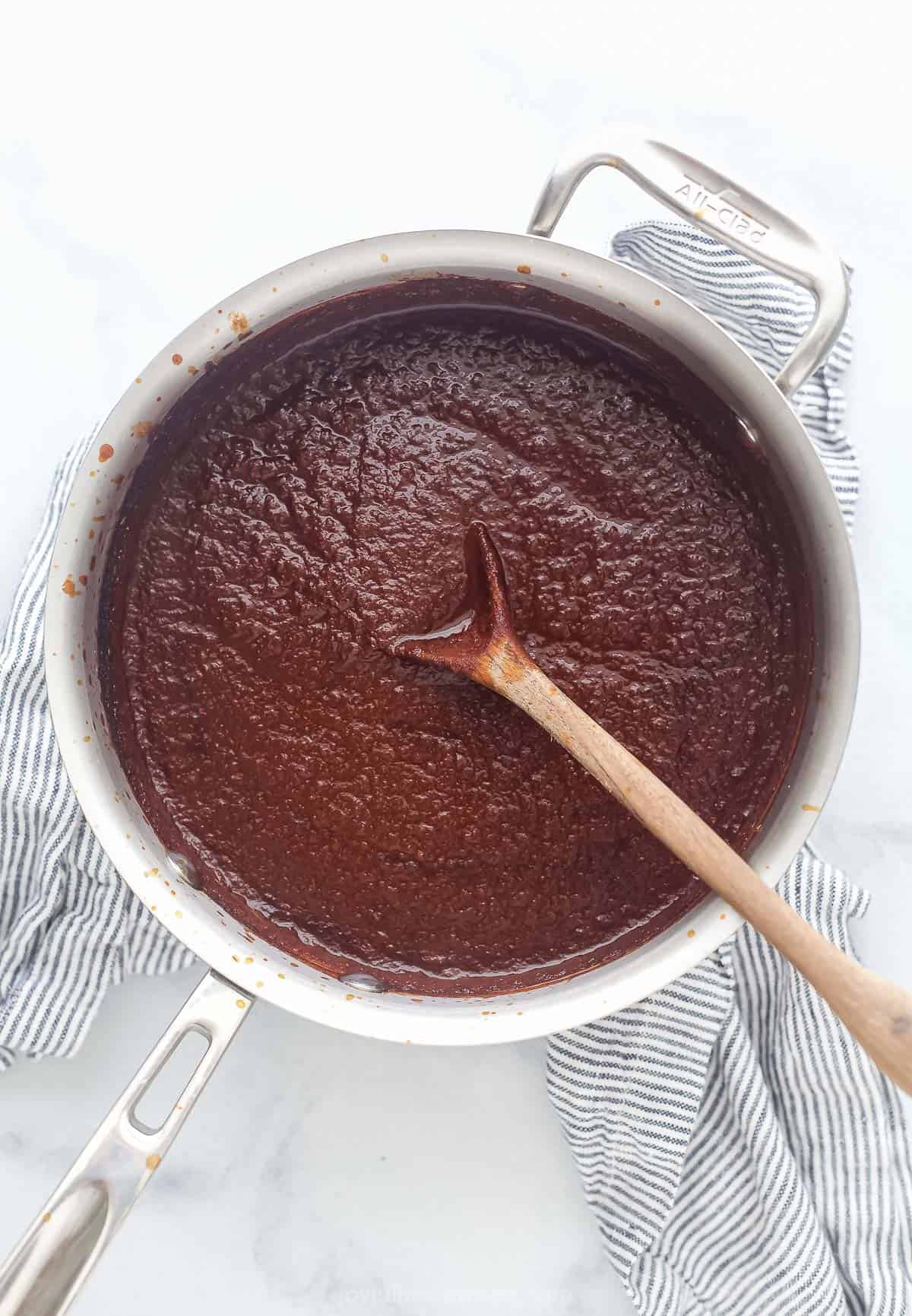 pureed red enchilada sauce in a pot with a wooden spoon