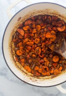 Cooked vegetables in a rich red paste in a large pot.