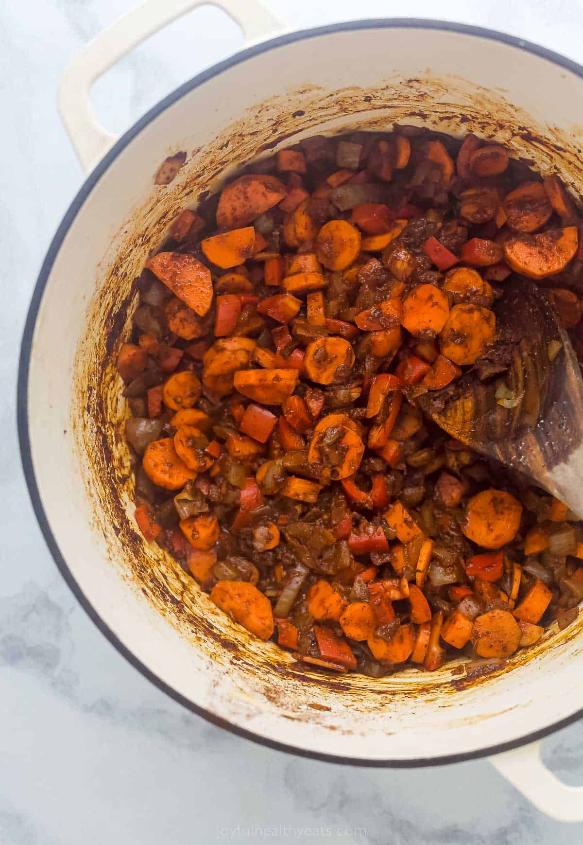 This Smoky Chicken Chili is loaded with fresh vegetables, beans, and a smoky flavor from chipotle peppers. It's ready to eat in 1 hour! cooked vegetables in a rich red paste in a large pot