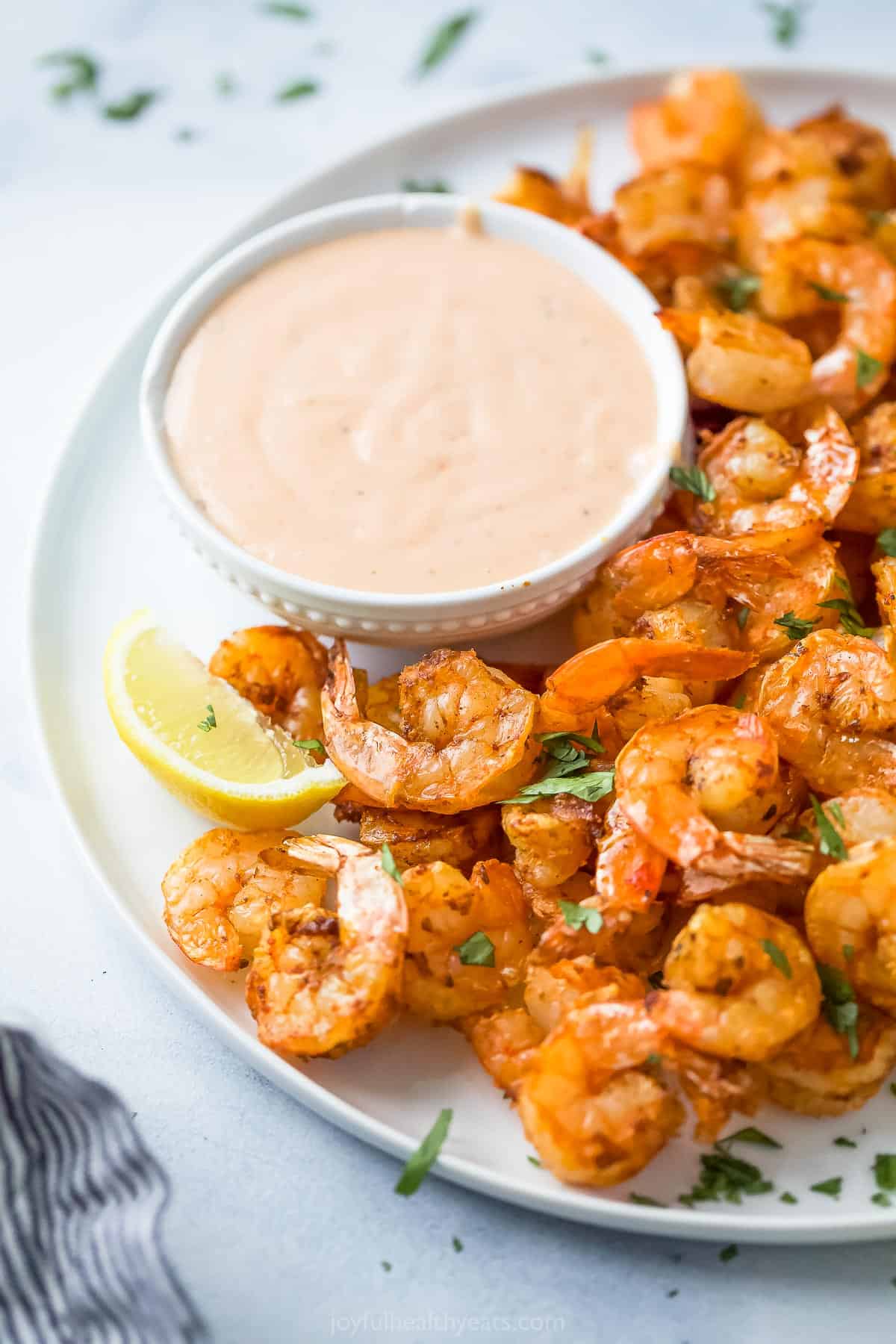 a plate of cooked shrimp with a side of dipping sauce