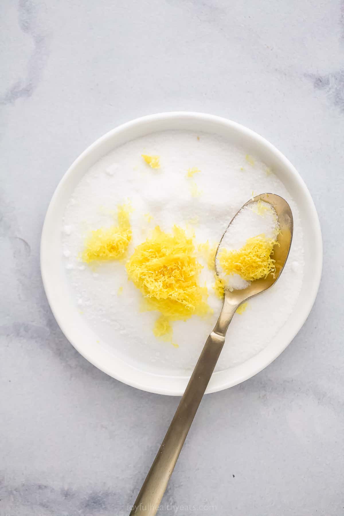 a plate with lemon zest and sugar with a spoon