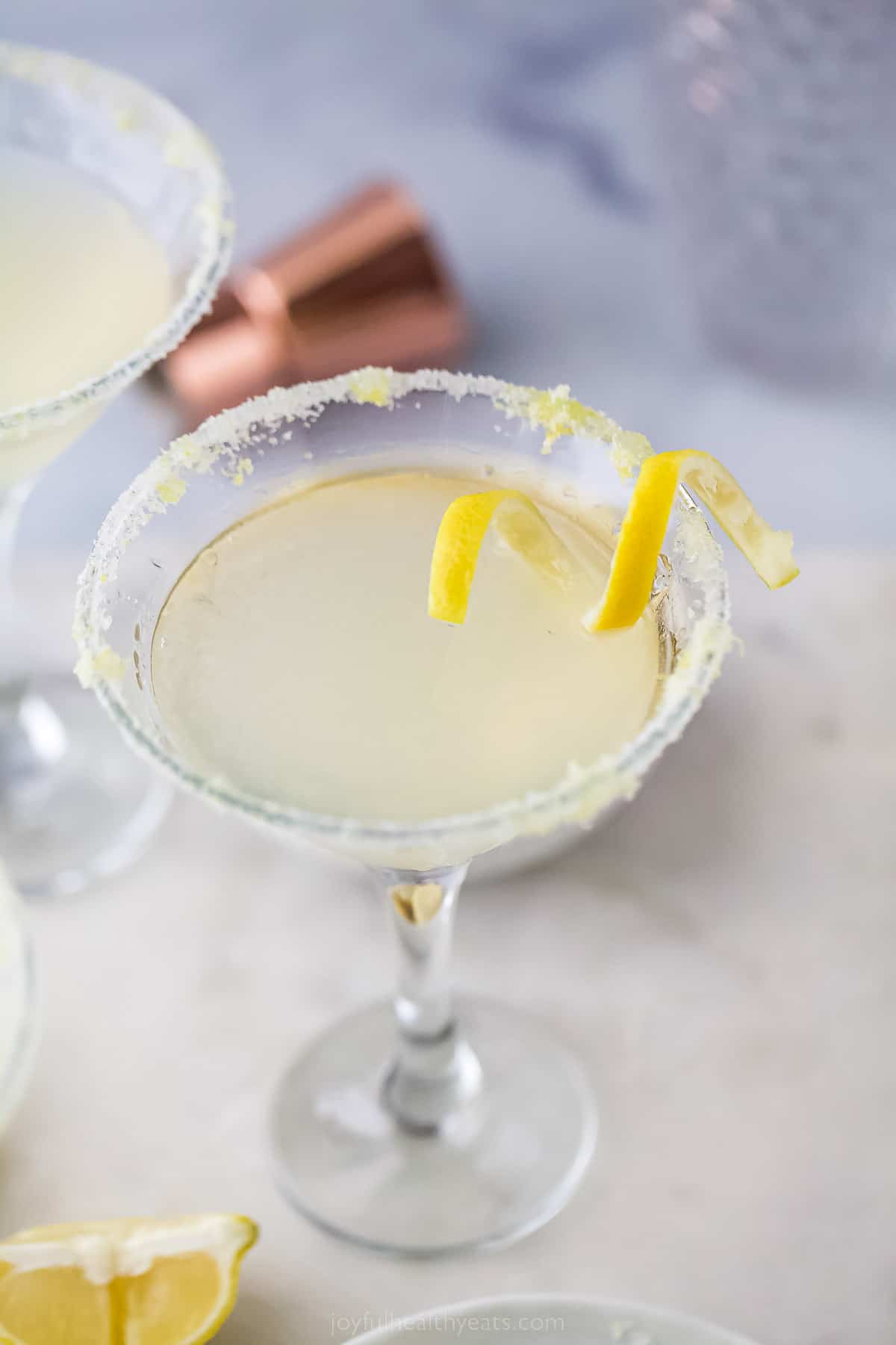 a lemon drop martini with a lemon rind garnish and sugared rim