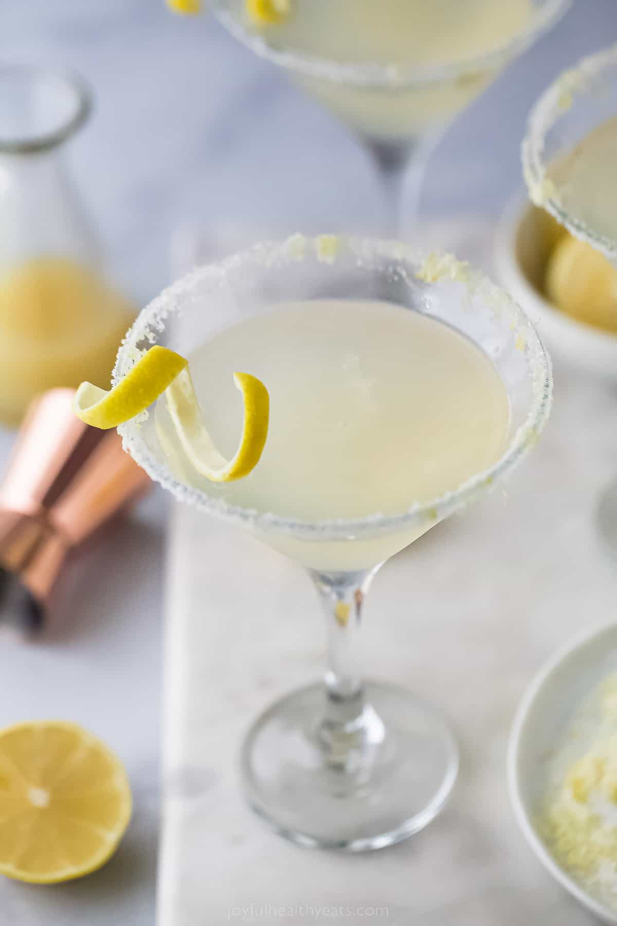 a lemon drop martini with a lemon rind garnish and sugared rim