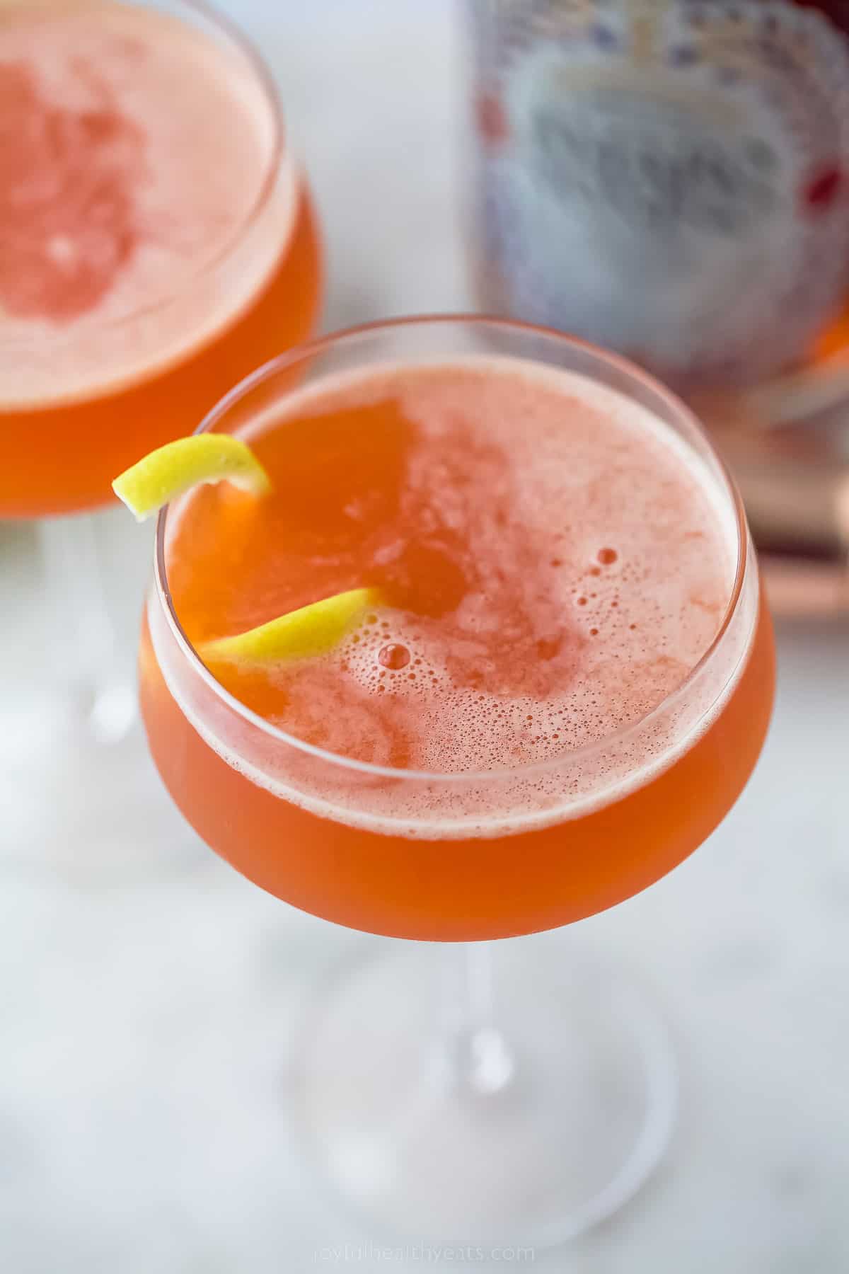 A pale orange paper plane drink with lemon garnish