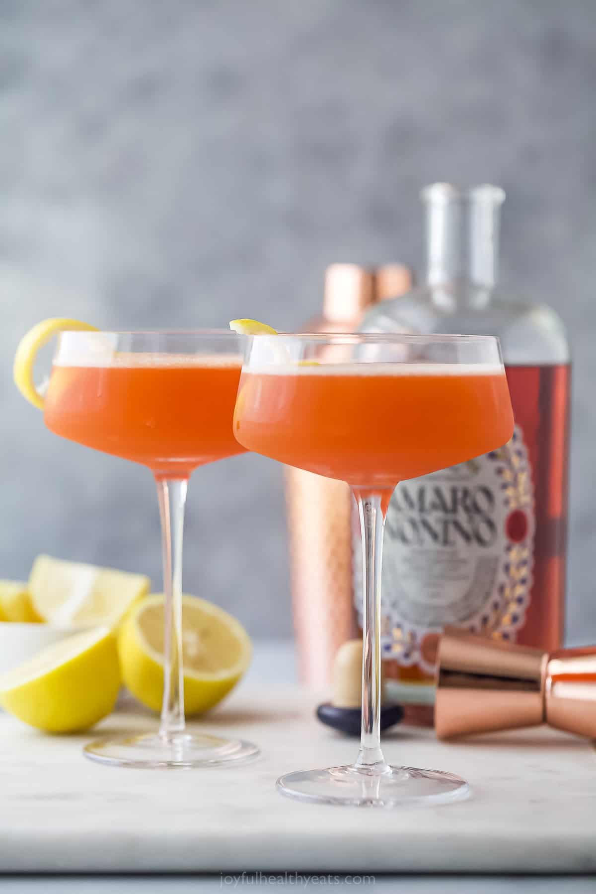 A pale orange paper plane drink with lemon garnish