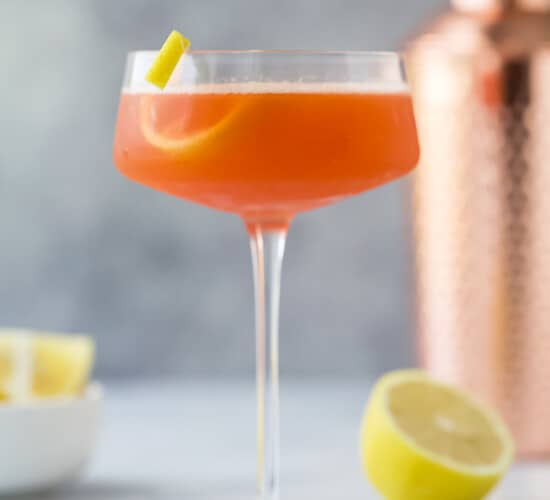 A paper plane cocktail with lemon garnish