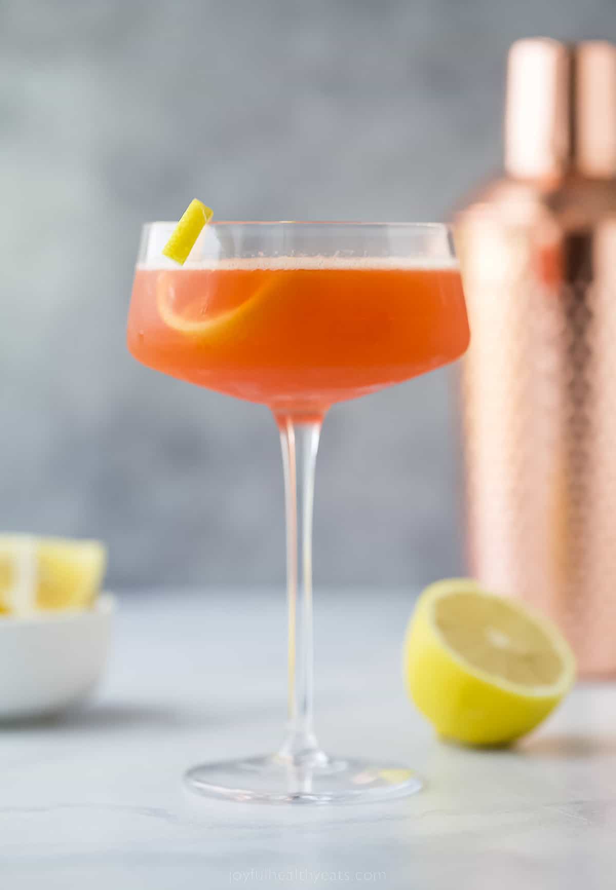 A paper plane cocktail with lemon garnish