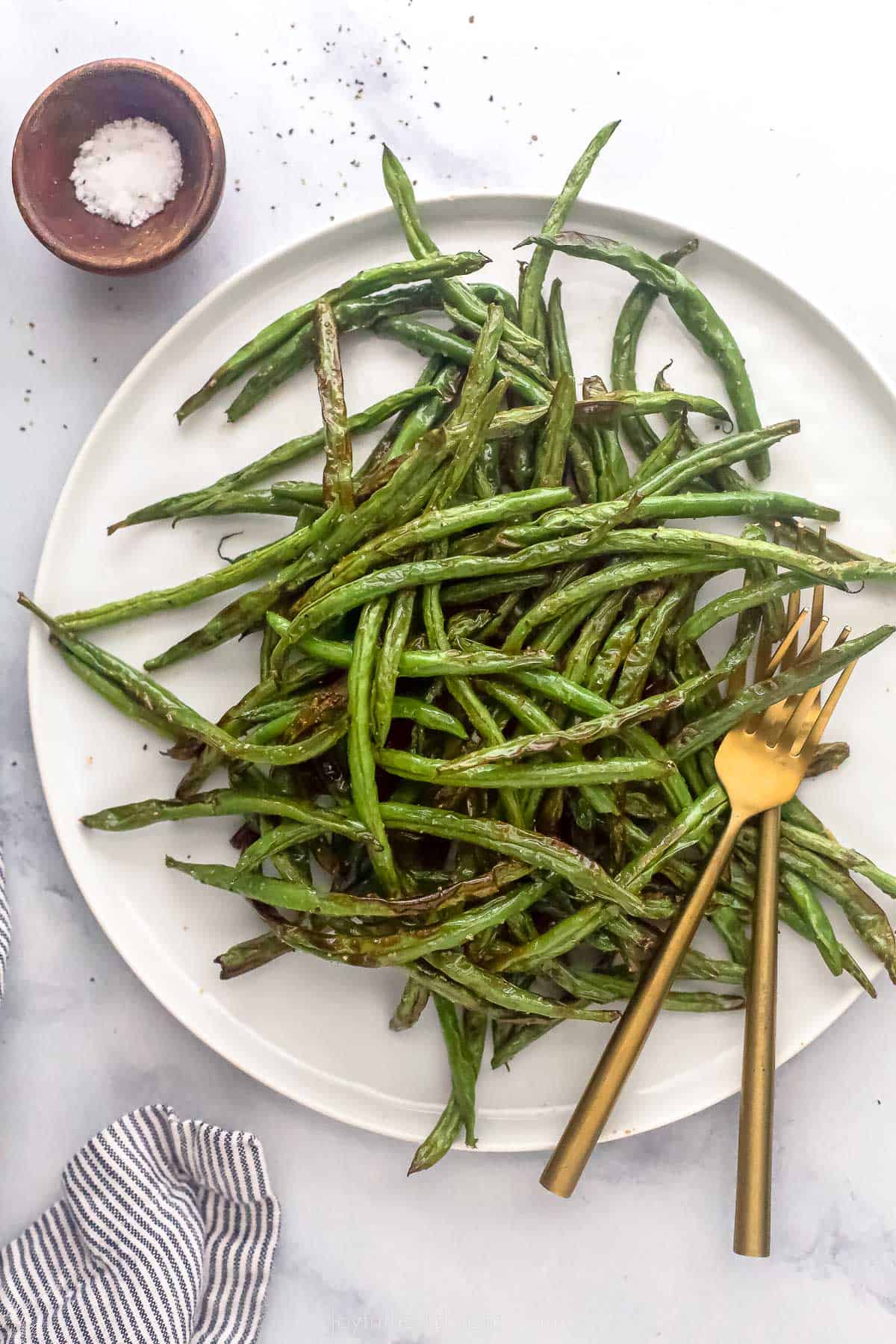 fried green beans on a white plate with a bronze fork