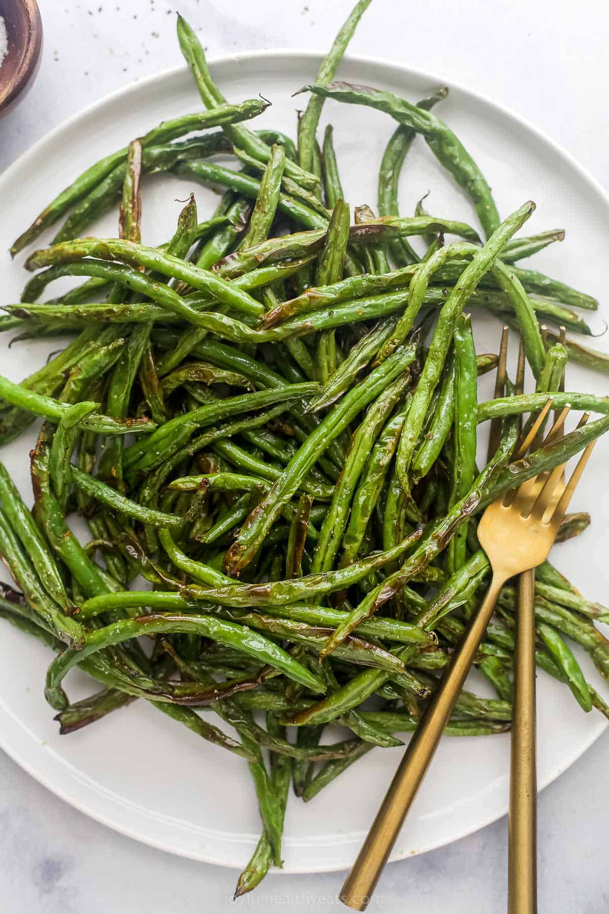 fried green beans on a white plate with a bronze fork