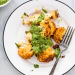 A plate with roasted cauliflower bits and green sauce on top