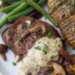 filet mignon with mustard and mushrooms on a plate with potato and green beans