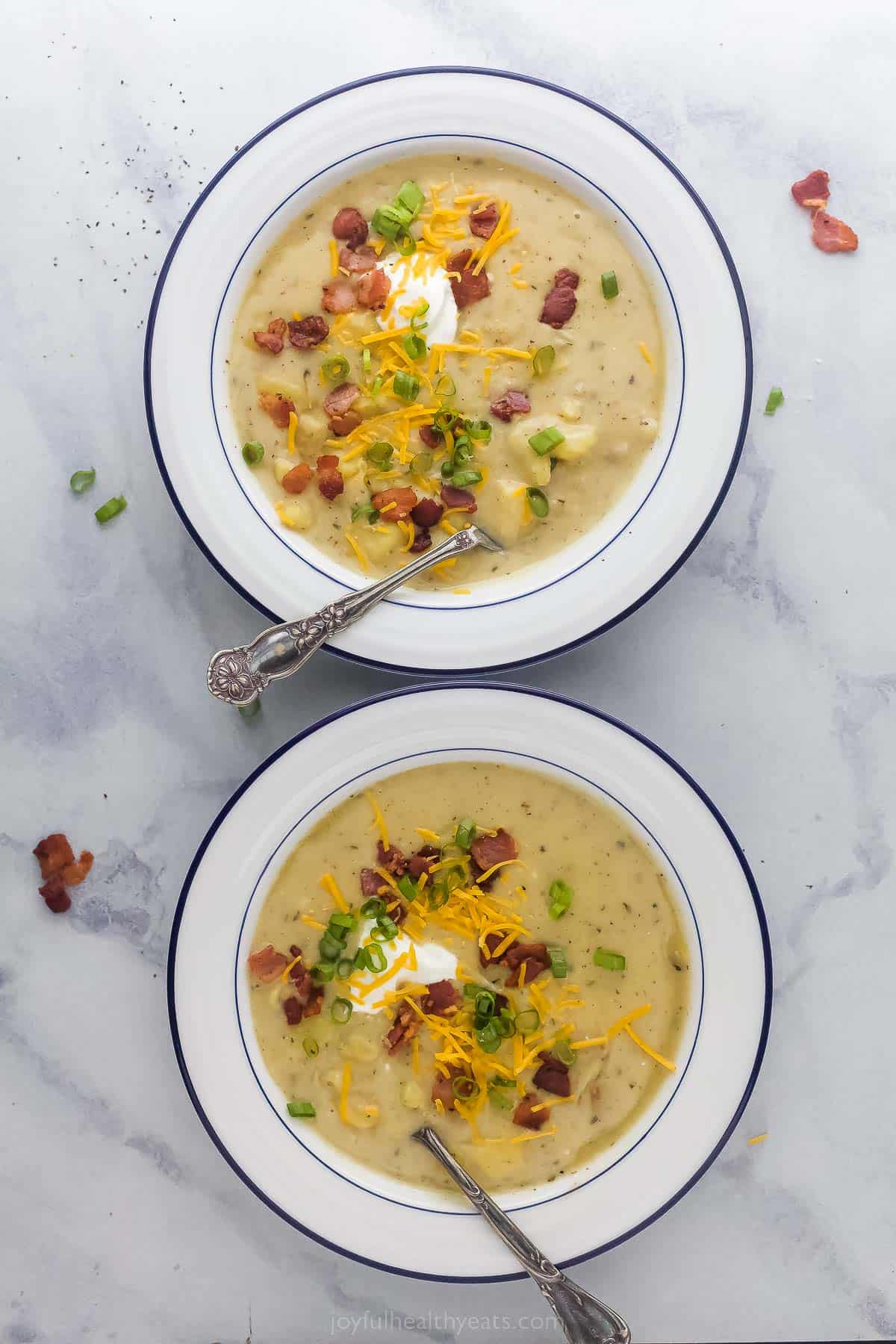 two bowls of a bowl of creamy potato soup with bacon and cheese garnish