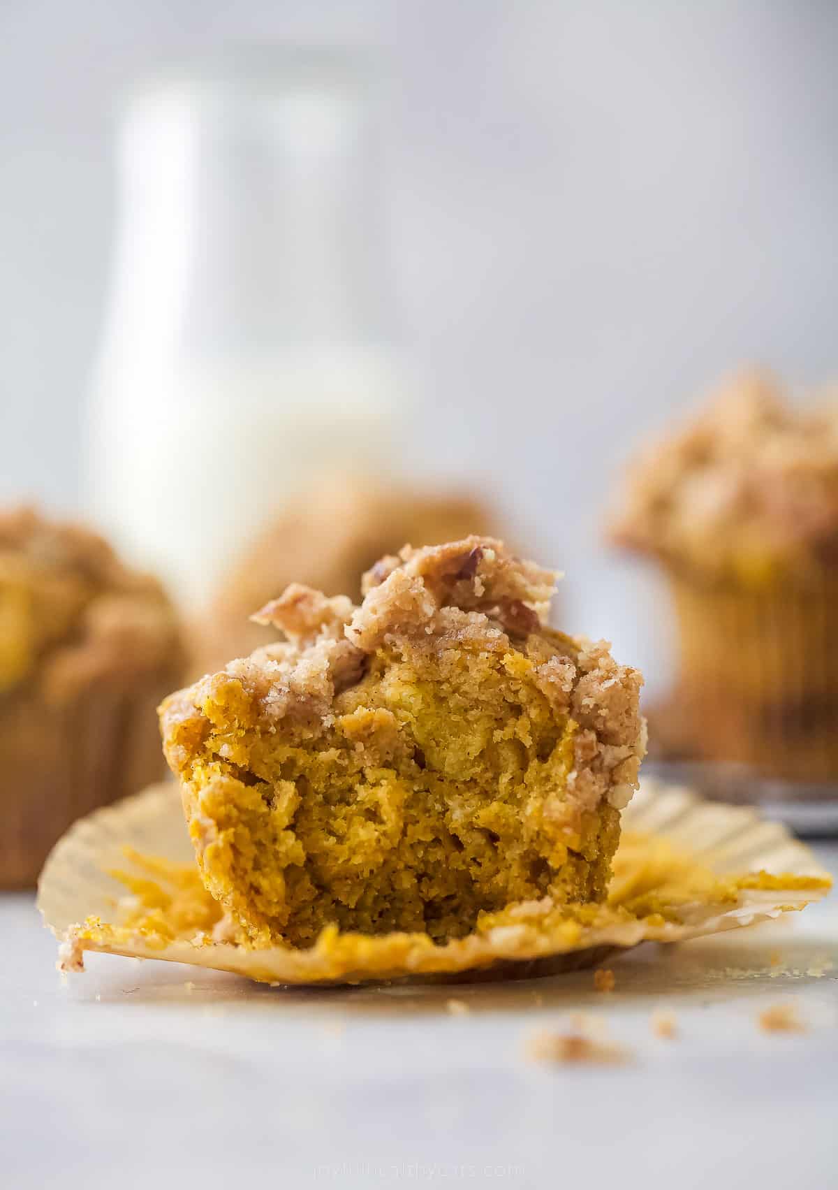 pumpkin muffin on a cupcake liner with a bite taken out of it