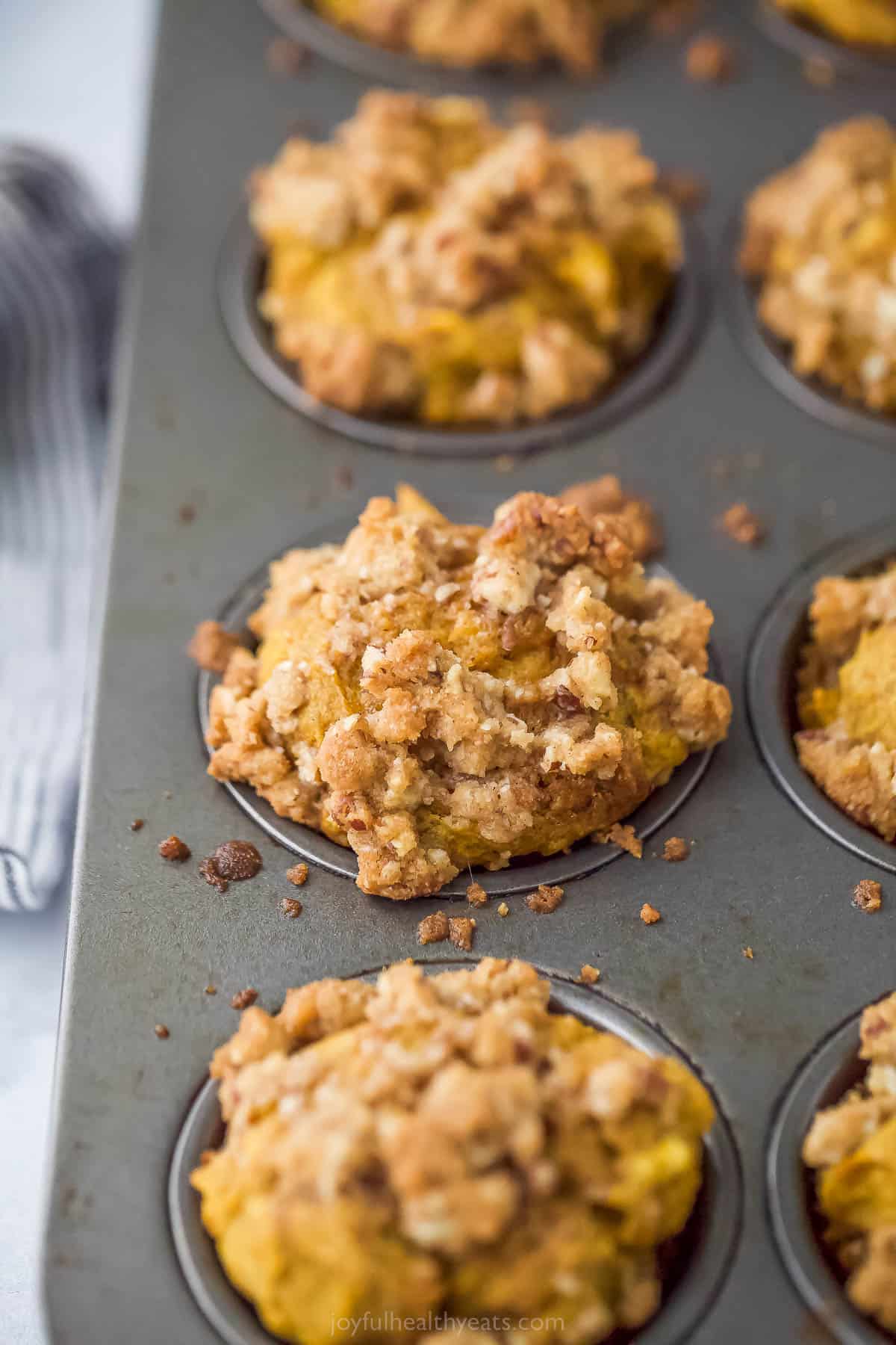 pumpkin muffins topped with pecan streusel in a muffin tin