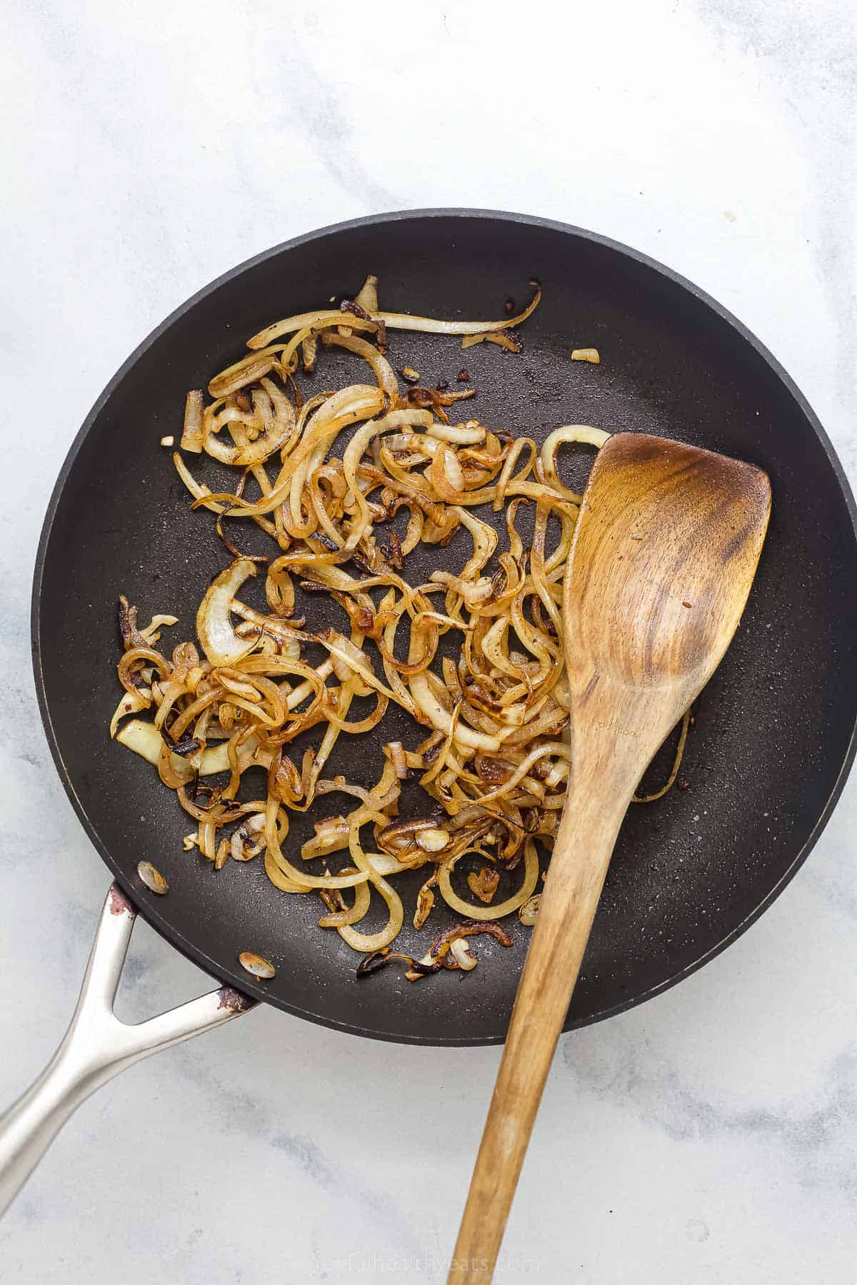 cooking sliced white onions in a saute pan