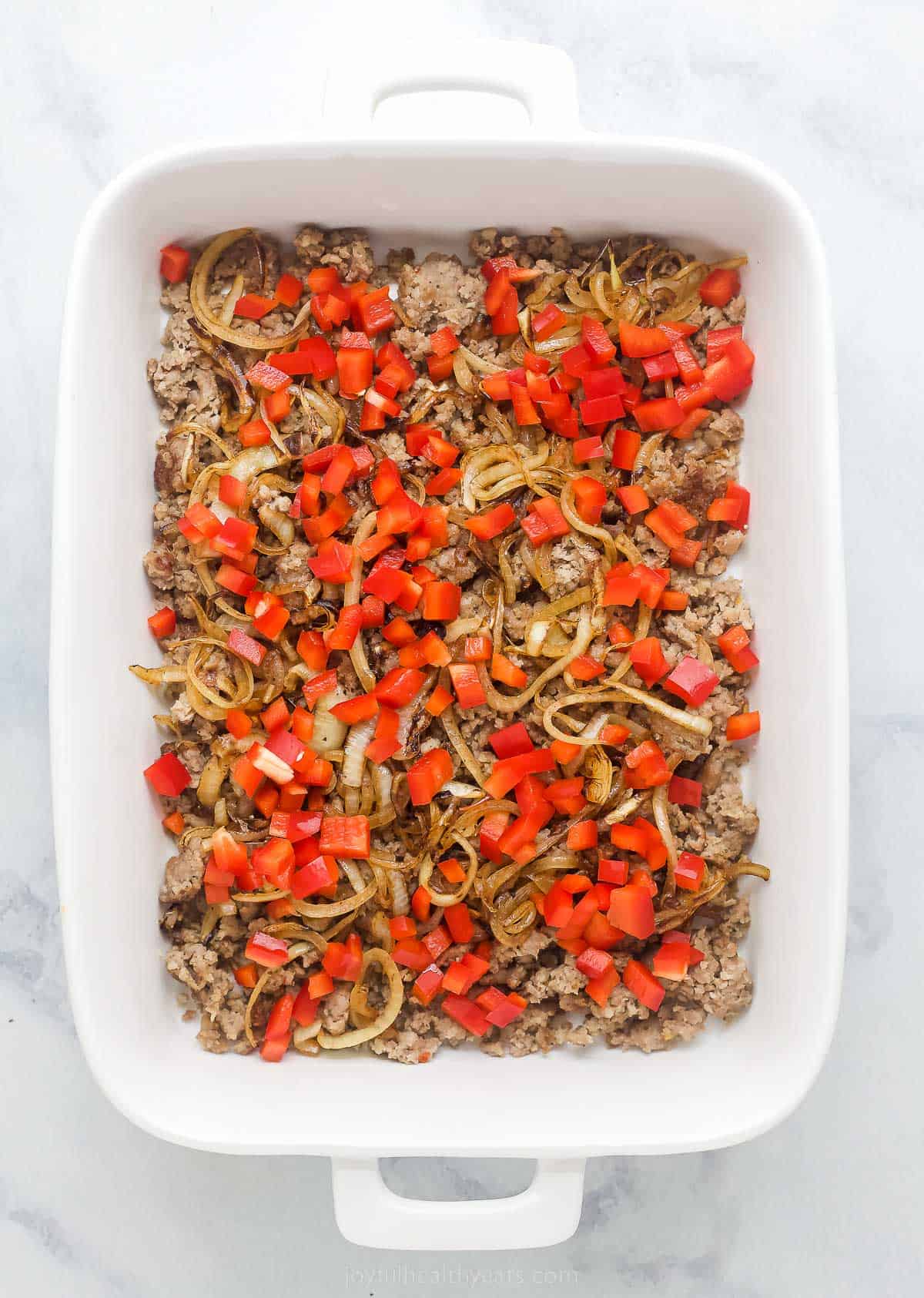 casserole dish with sausage, onions, and red peppers