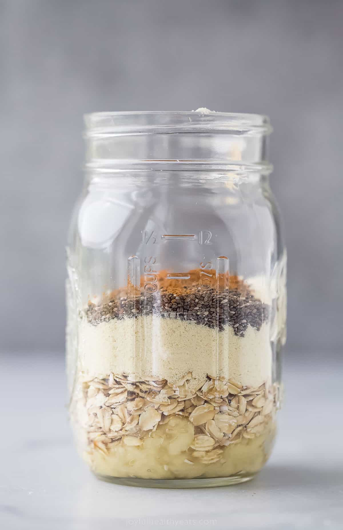 a large mason jar with dried layers of oats, cinnamon, and protein powder