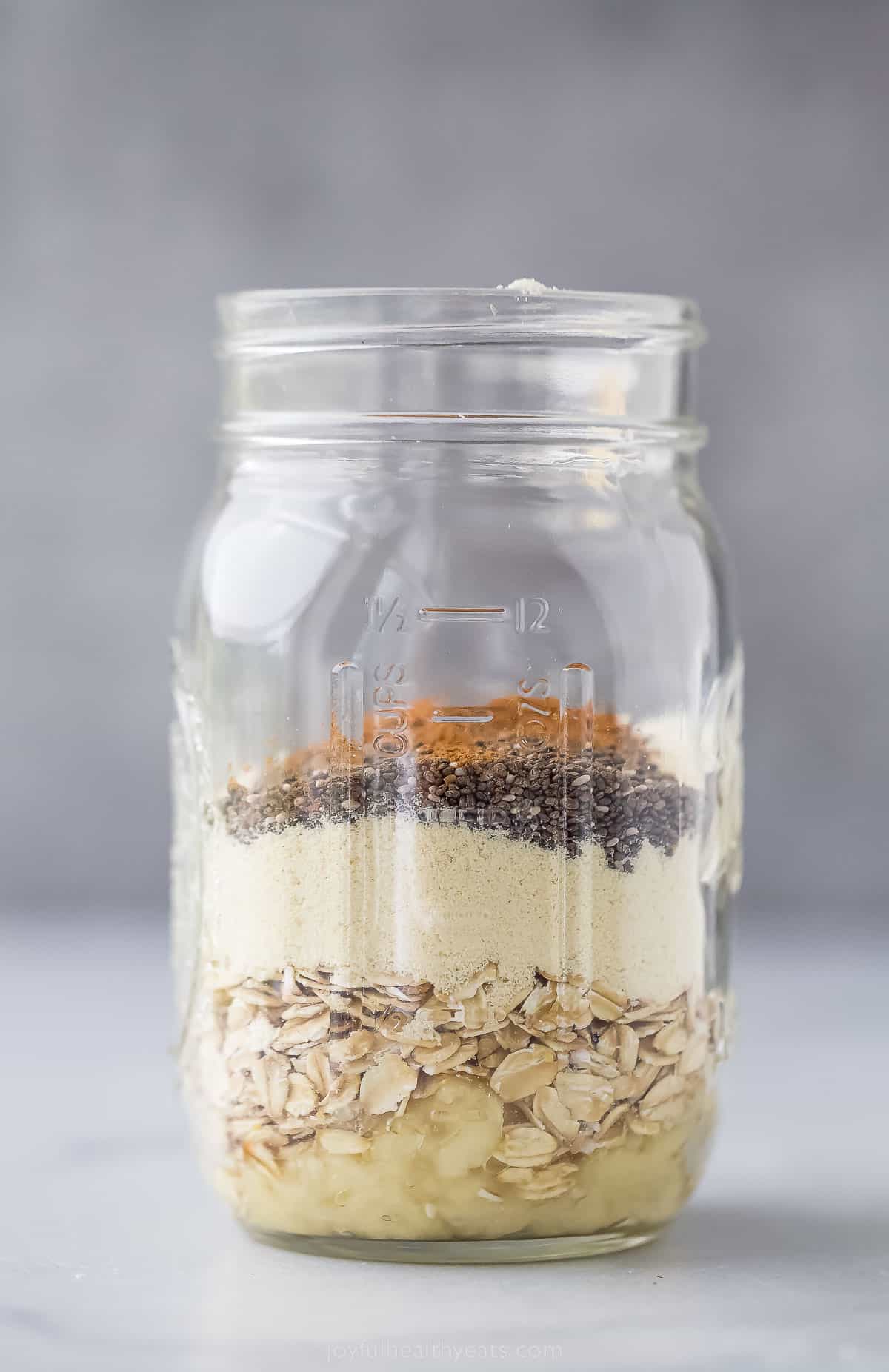 These simple Protein Overnight Oats are a great make-ahead breakfast. These flavorful oats have vanilla protein powder, banana, and cinnamon. a large mason jar with dried layers of oats, cinnamon, and protein powder