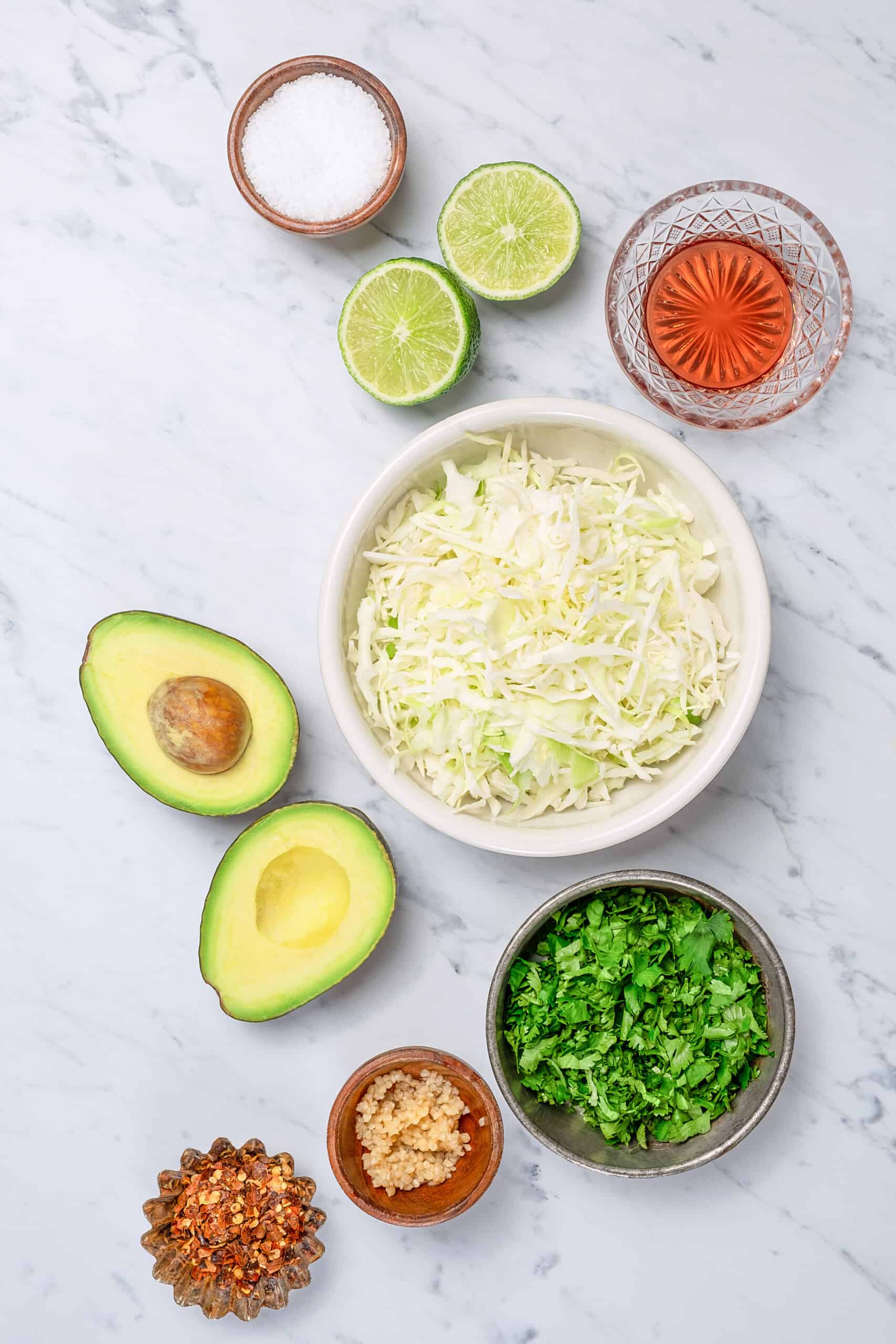 These Easy Salmon Tacos are topped with creamy slaw, pickled onions, and cotija cheese. They are flavorful, healthy, and ready in 30 minutes! ingredients to make a creamy slaw like cabbage, avocados, herbs, and lime juice