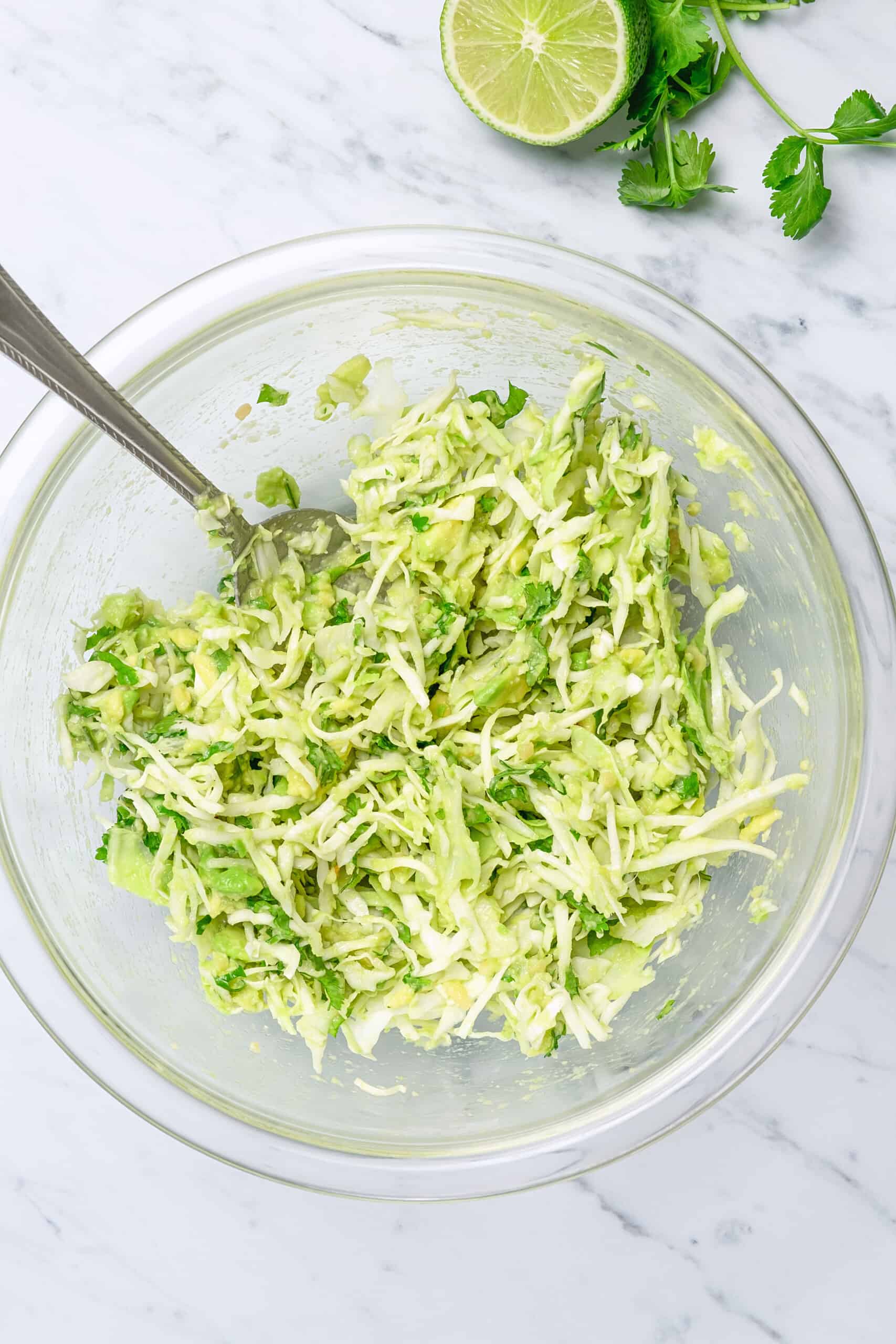 tossing cabbage with avocados in a bowl