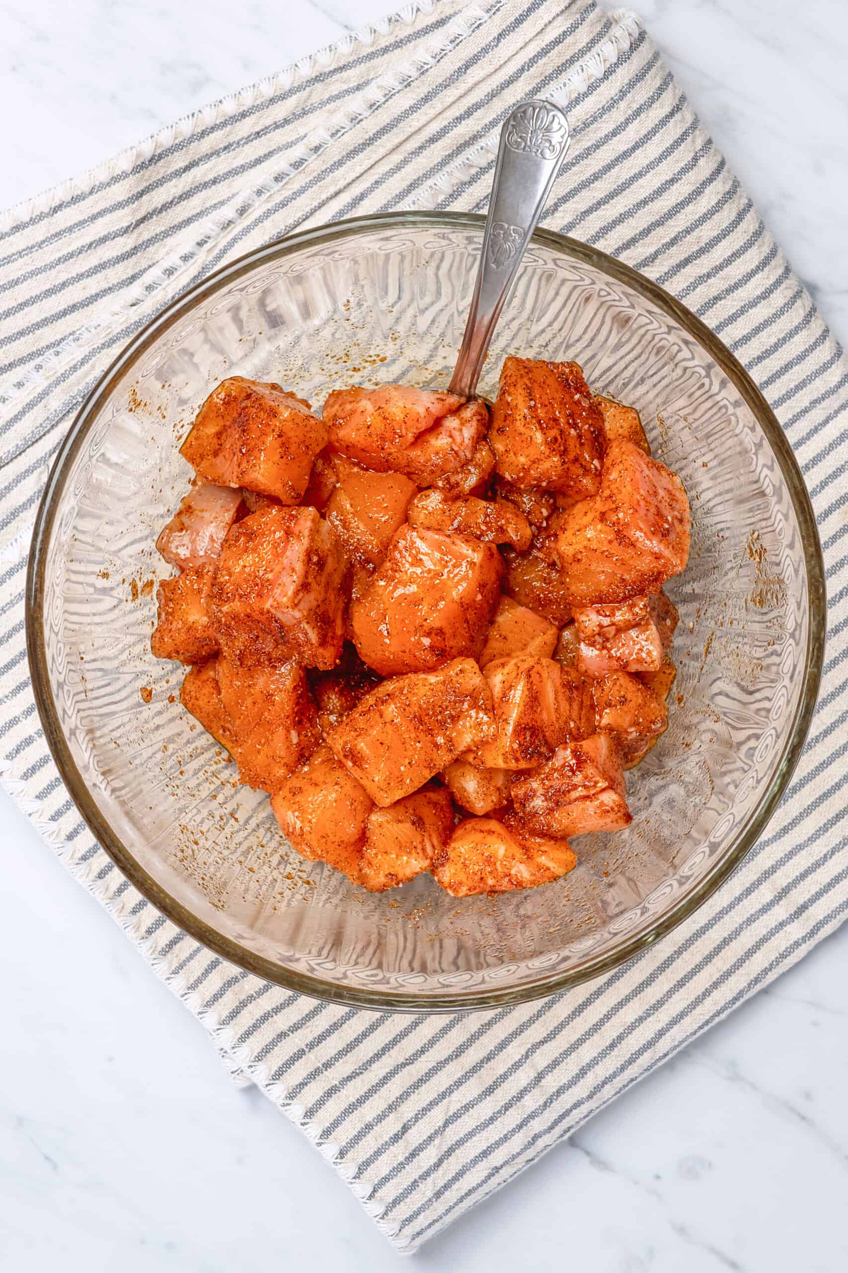 mixing raw salmon in a bowl with seasonings