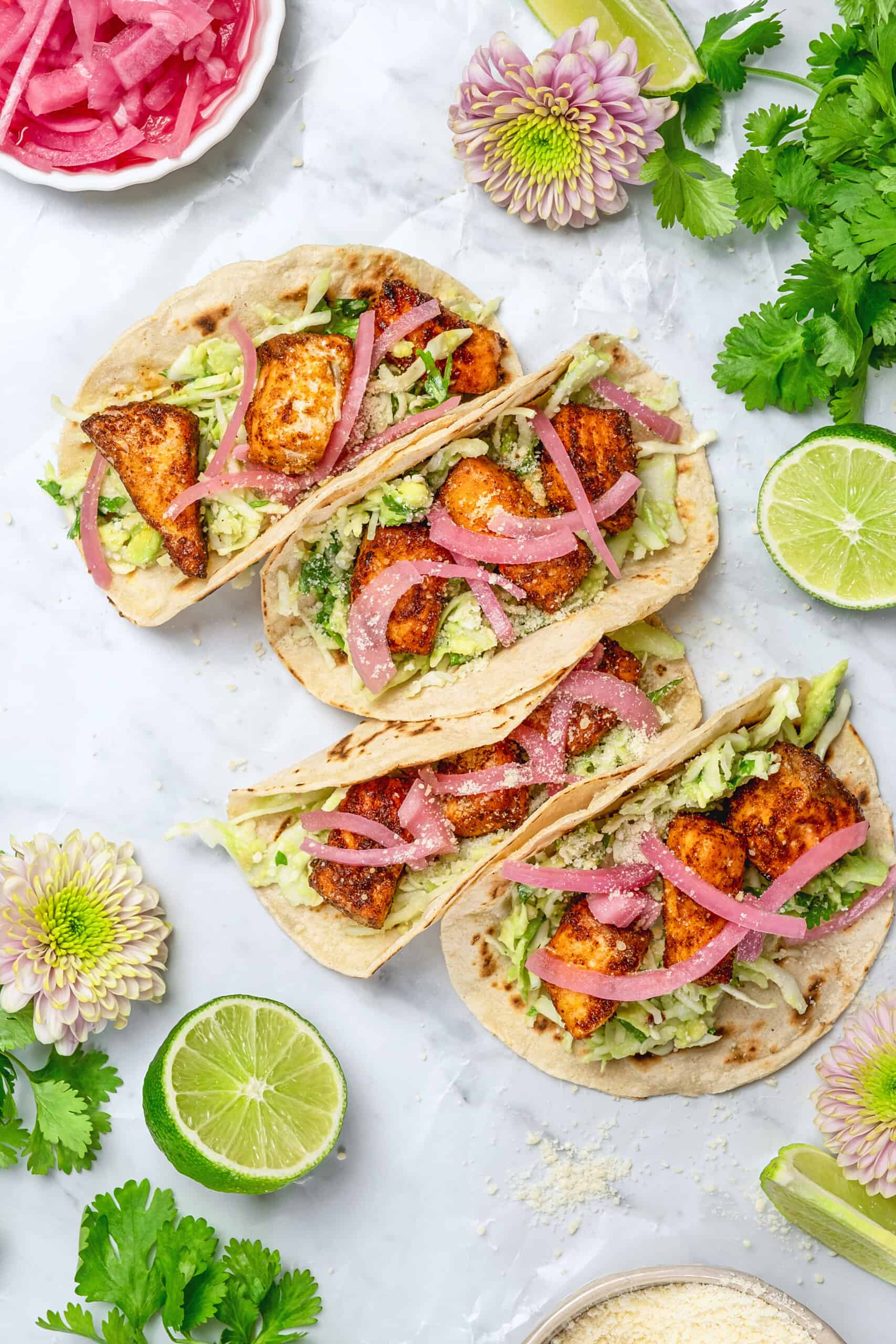 Salmon tacos with creamy sauce and red onion garnish.