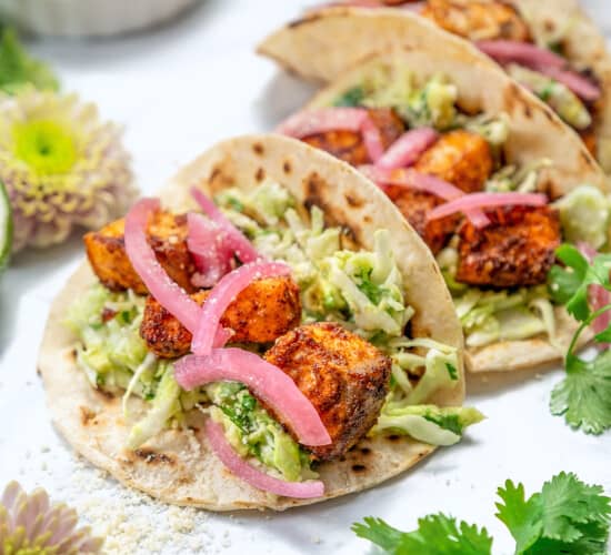 easy salmon tacos with creamy sauce and red onion garnish