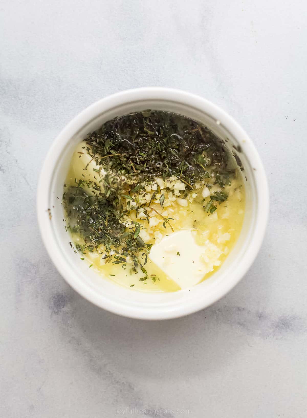 a bowl with melted butter and herbs