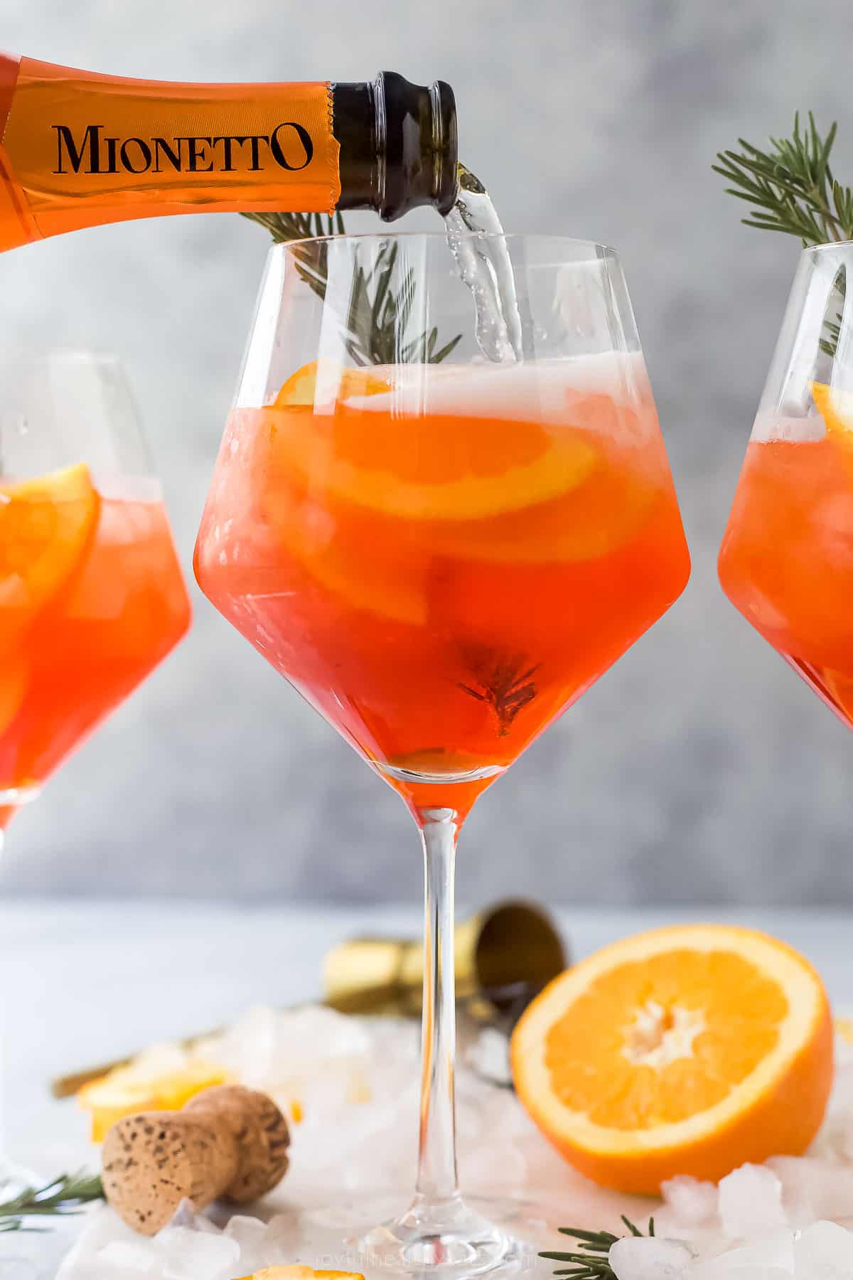 a glass of Holiday Aperol Spritz with rosemary garnish