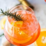 a glass of Holiday Aperol Spritz with rosemary garnish