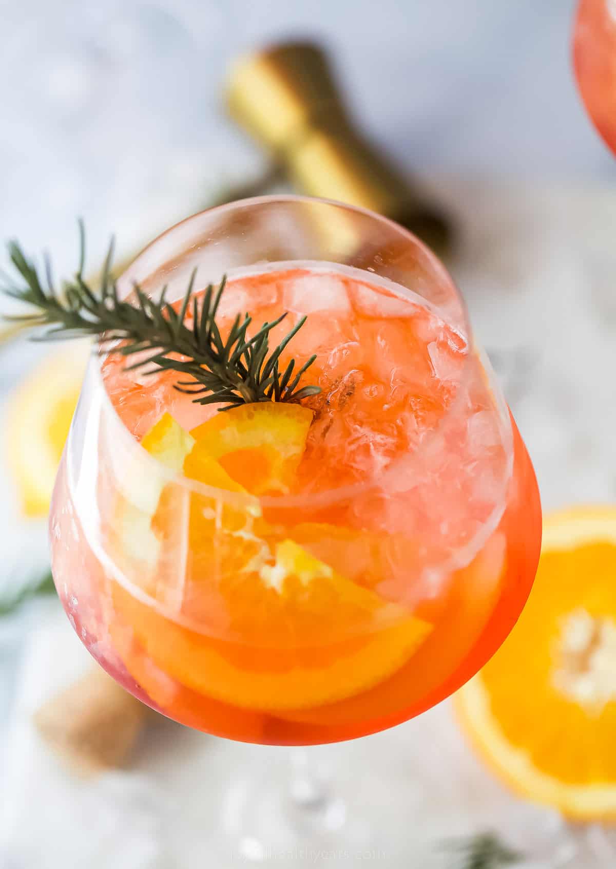 a glass of Holiday Aperol Spritz with rosemary garnish