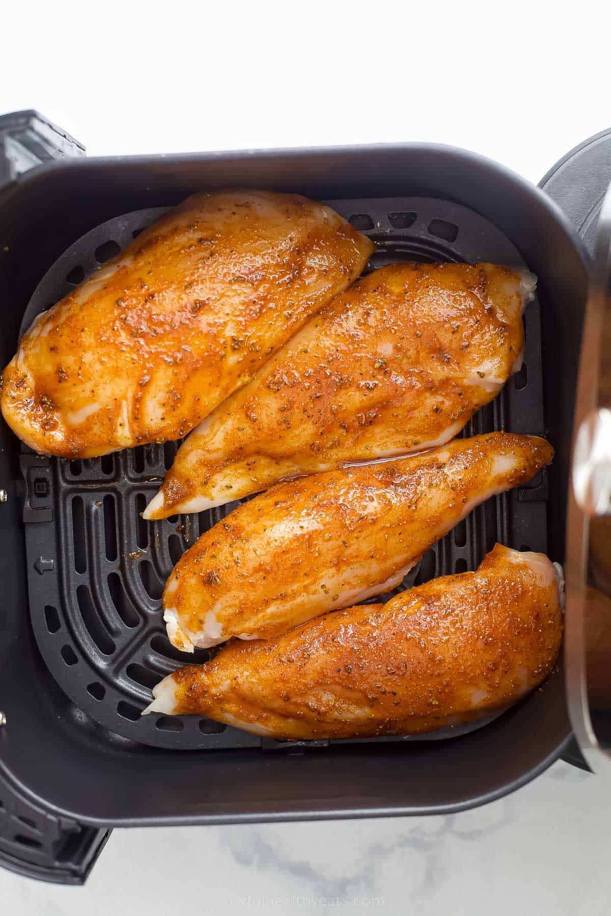 uncooked chicken breasts in an air fryer
