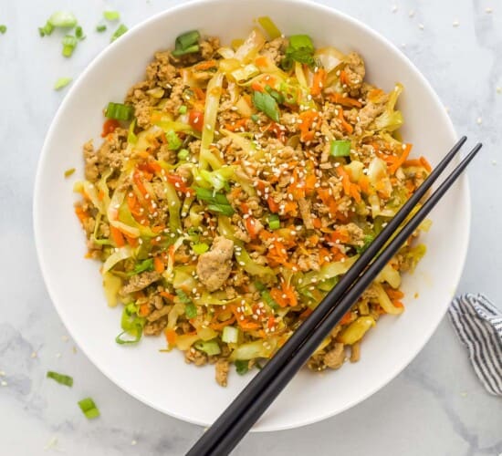 egg roll in a bowl plated in a white bowl which is ground turkey, cabbage, and carrots tossed a soy-based sauce