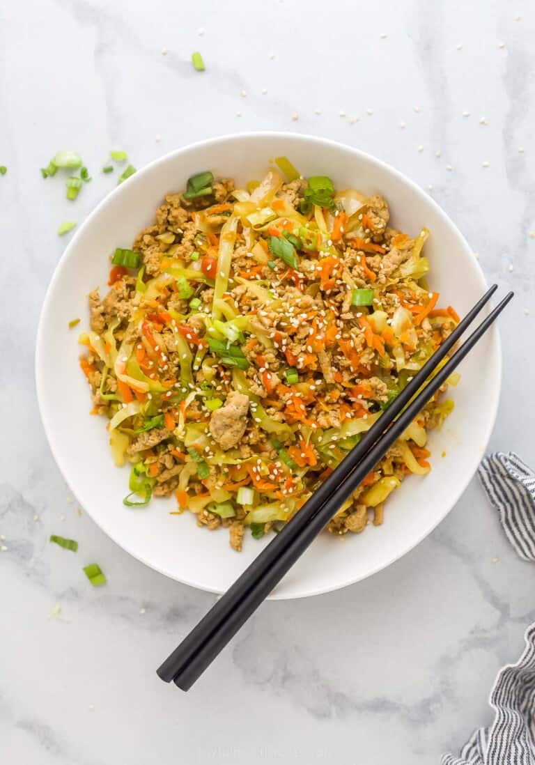 egg roll in a bowl plated in a white bowl which is ground turkey, cabbage, and carrots tossed a soy-based sauce