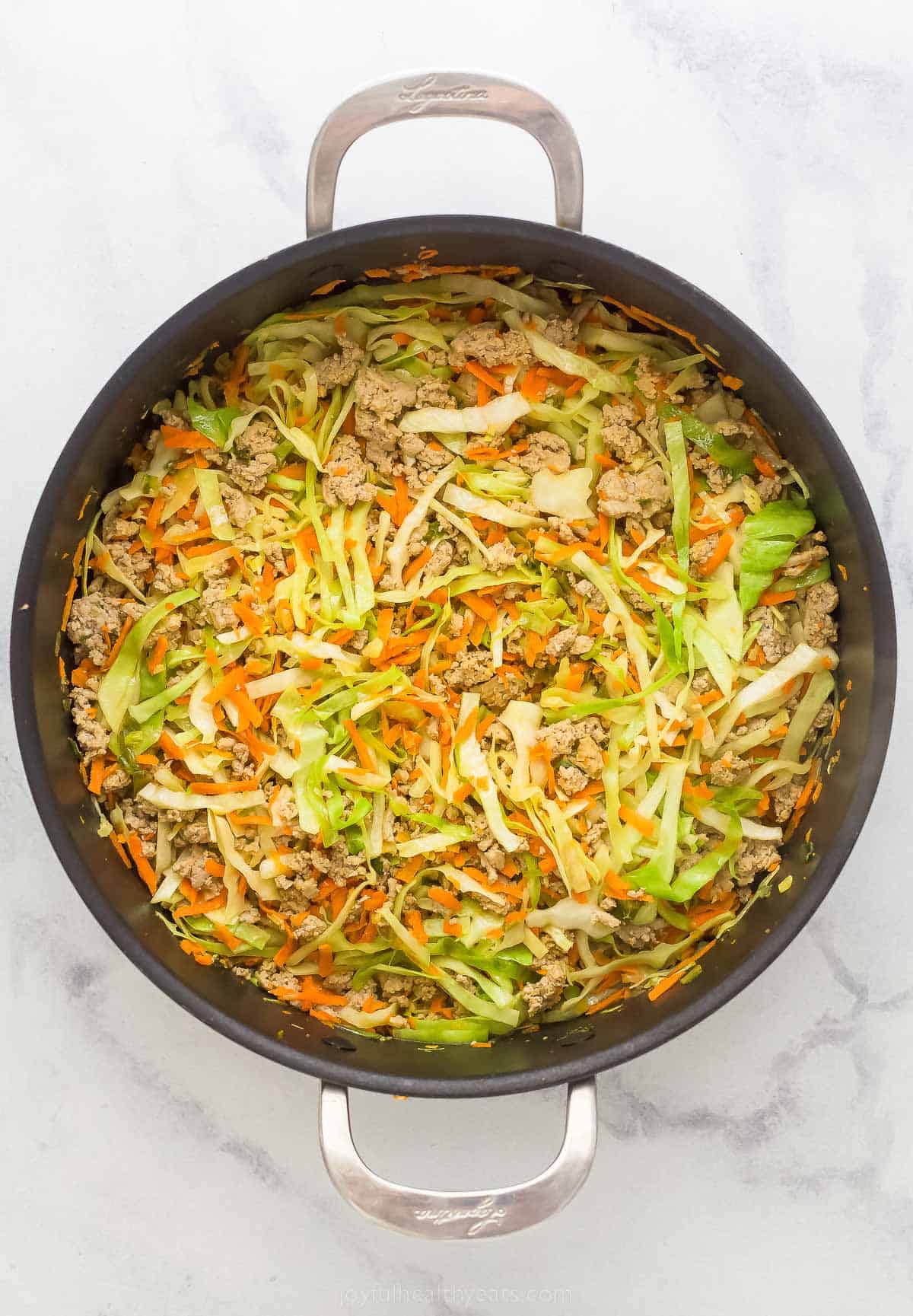 cooked carrots, cabbage, and turkey in a pan