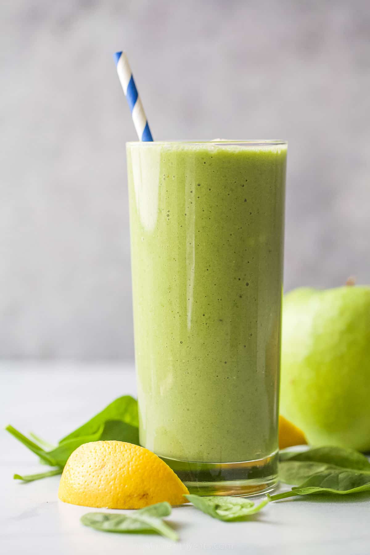 a glass with green smoothie and straw