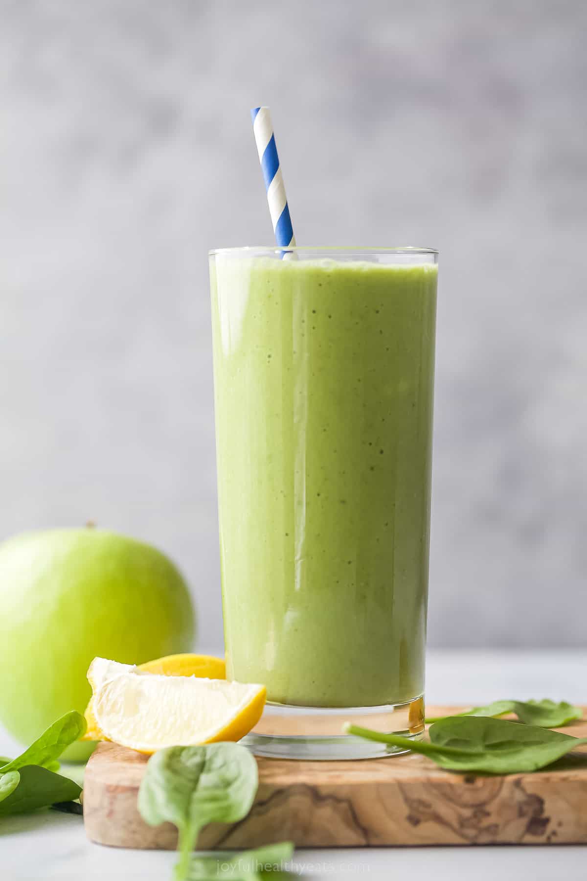 green detox smoothie in a tall glass with straw