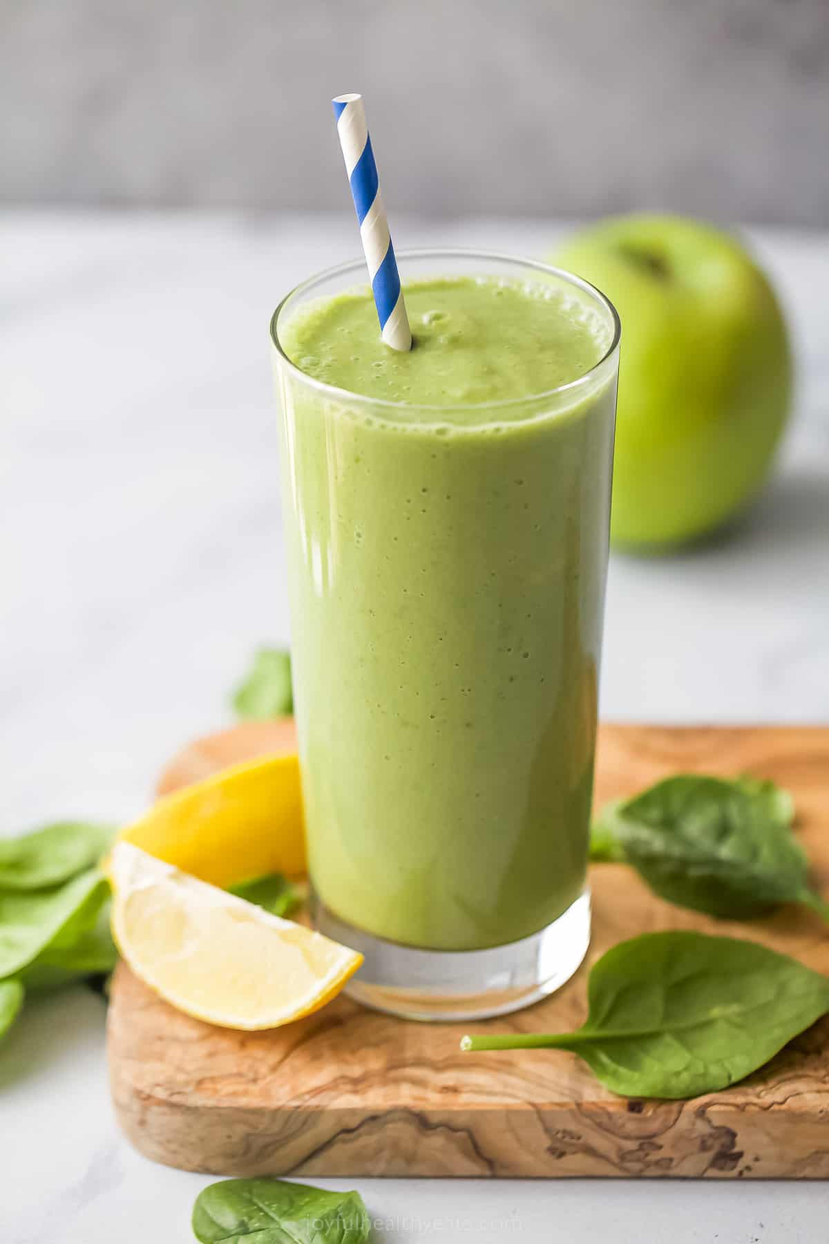 green detox smoothie in a tall glass with straw