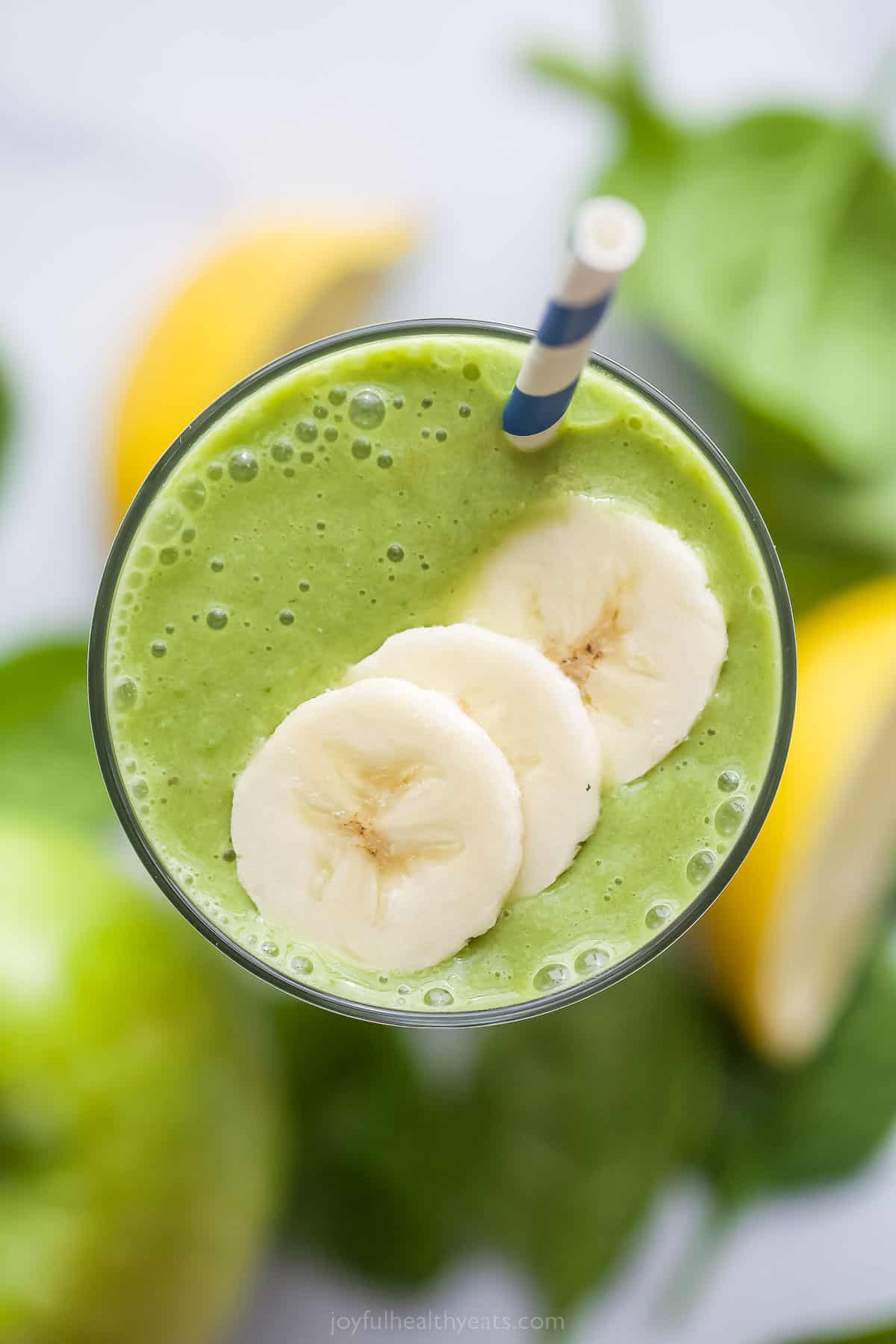 This Slimming Detox Smoothie is the perfect green smoothie! It has spinach, apples, pineapple, and banana, plus a dash of cinnamon! top view of a green smoothie with banana slices as garnish