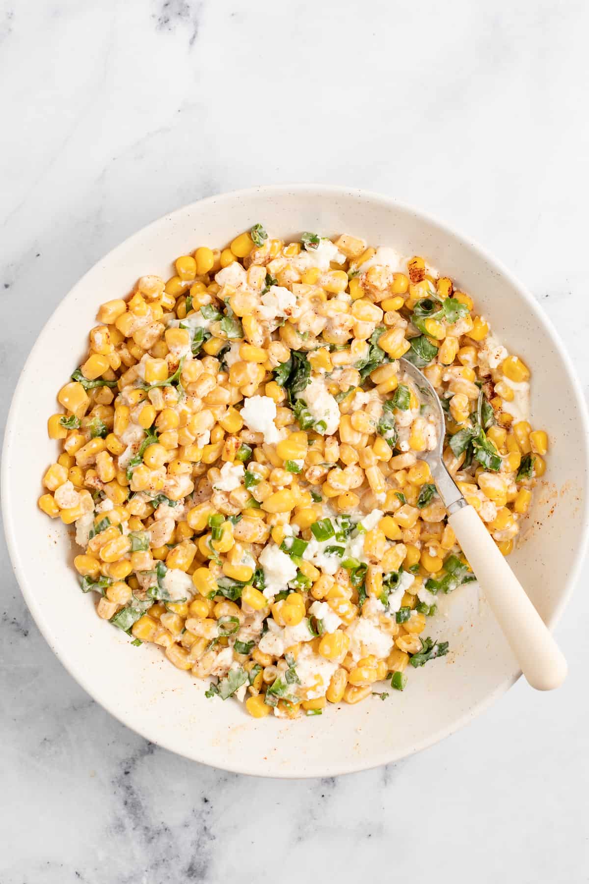 Mexican Street Corn Salad in a bowl which is made of corn, herbs, spices, and a creamy dressing