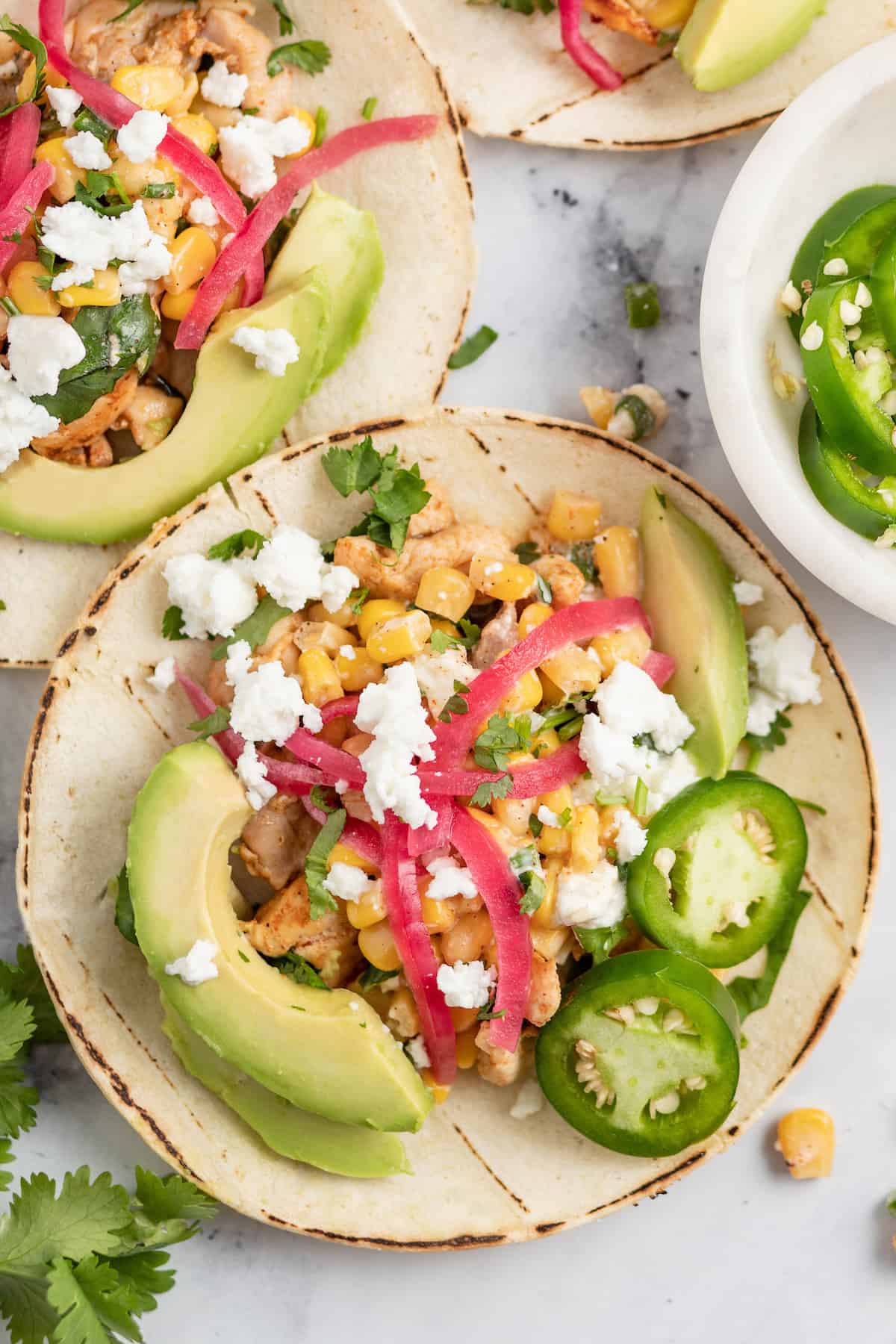 Chicken Street Tacos with pickled onions, Mexican Street Corn salad, and sliced avocados