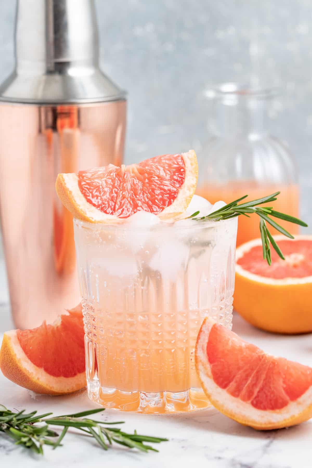 This tangy and refreshing Greyhound Cocktail is made with just 3 ingredients. It has fresh grapefruit juice, vodka, and some bubbles! greyhound cocktail made with grapefruit juice and sparking water in a low ball glass with a cocktail shaker behind it