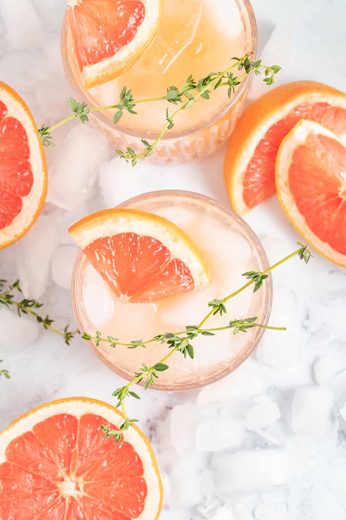 top view of a grapefruit cocktail with a grapefruit wedge and fresh herb garnish