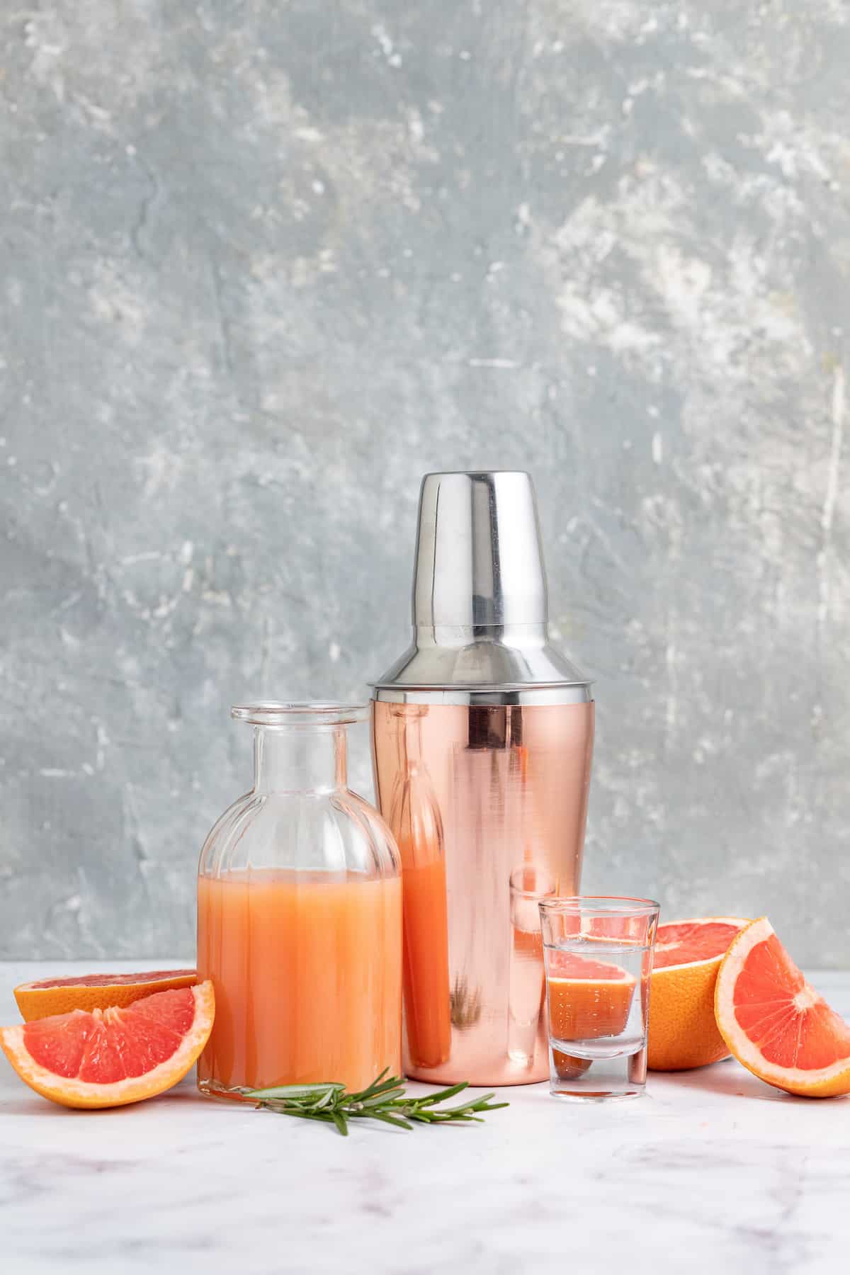 This tangy and refreshing Greyhound Cocktail is made with just 3 ingredients. It has fresh grapefruit juice, vodka, and some bubbles! a display of cocktail making ingredients to make a greyhound which includes grapefruit juice, fresh grapefruit, and a cocktail shaker