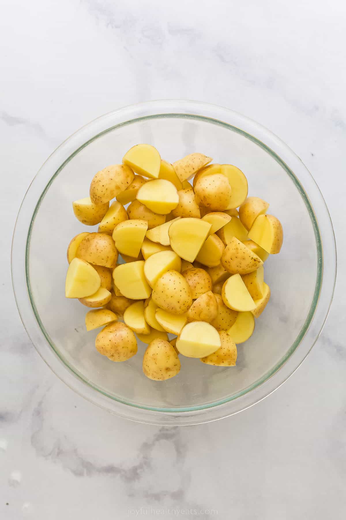 These are the best Air Fryer Roasted Potatoes! Tender on the inside and crispy on the outside. These potatoes are herby and delicious. a bowl of cut up potatoes